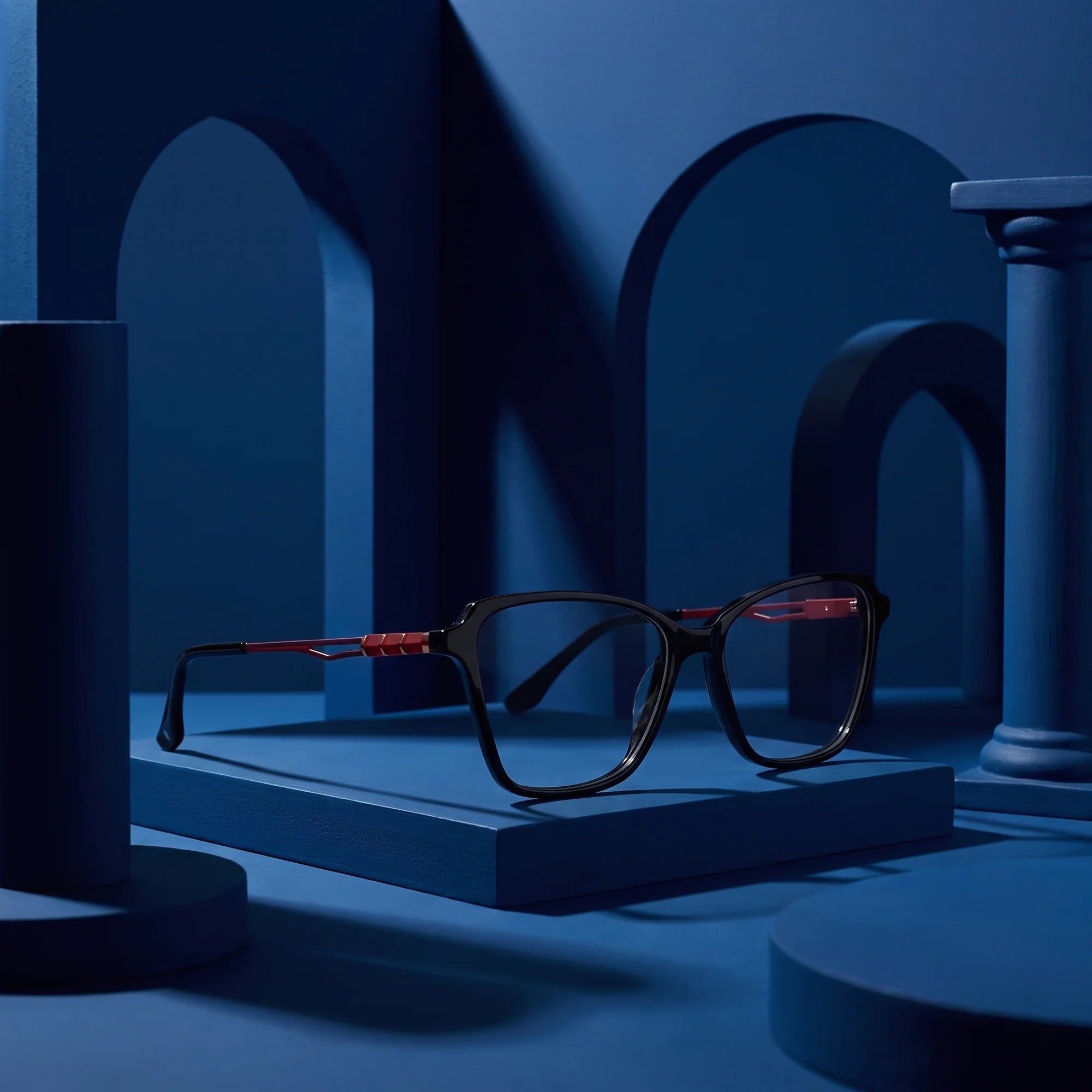 Fiore 1006 eyeglasses in black – displayed on a midnight blue podium among arches