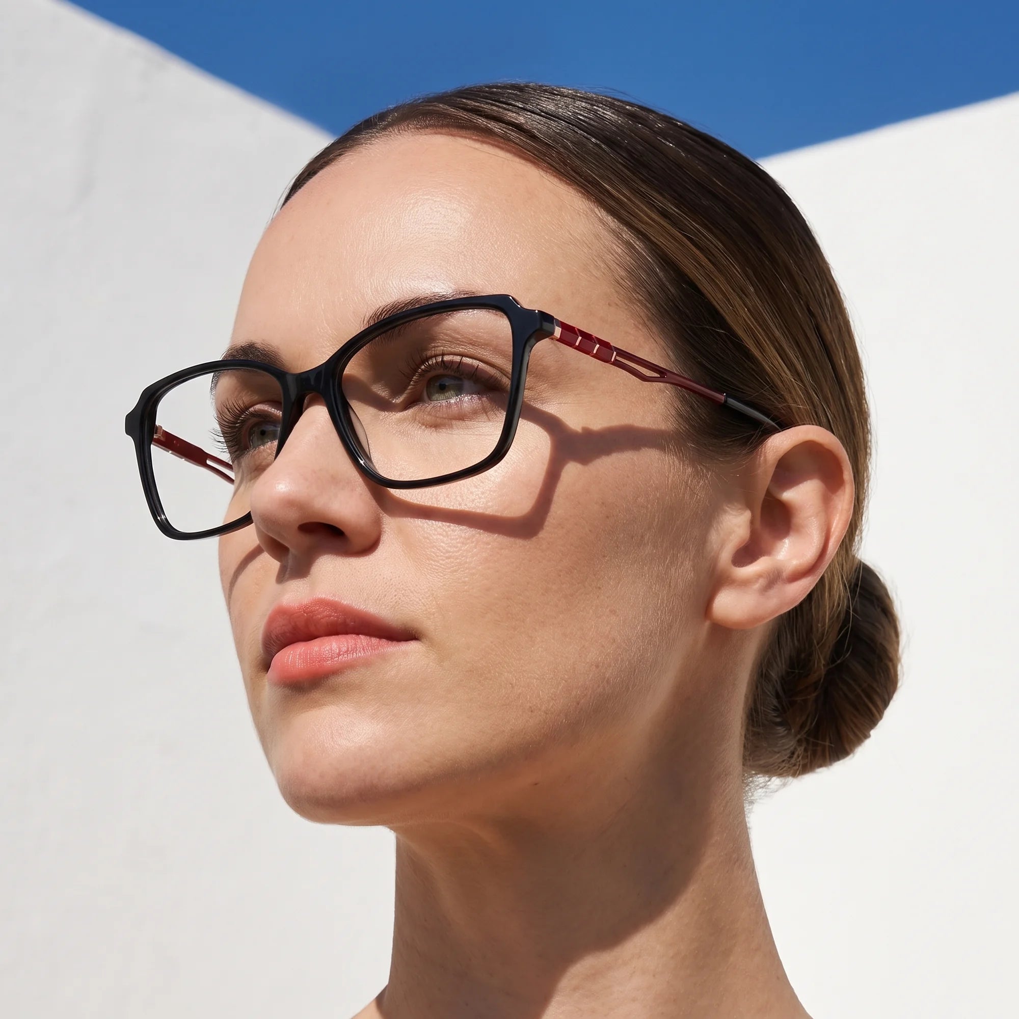 Fiore 1006 eyeglasses in black, worn by a model – campaign portrait, sunlit Balearic whitewash and deep blue sky