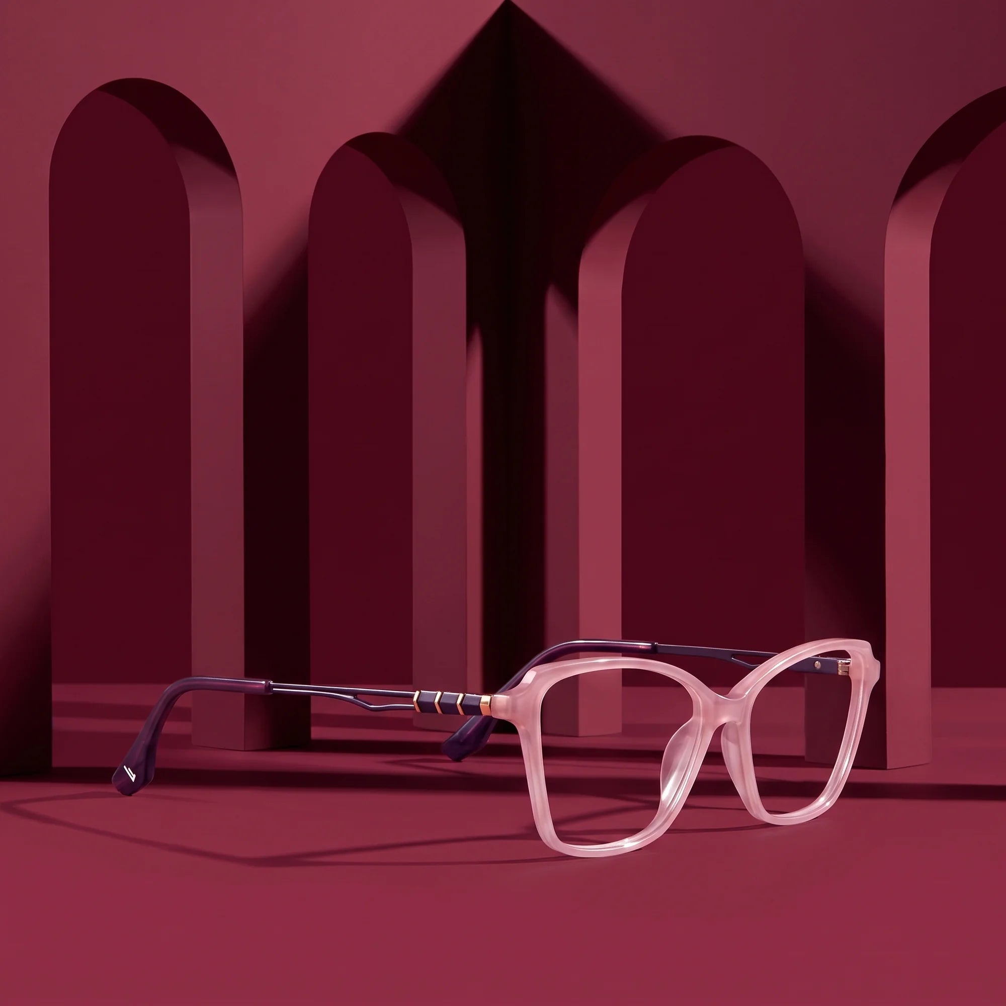 Fiore 1006 eyeglasses in pink – displayed on a burgundy podium among arches