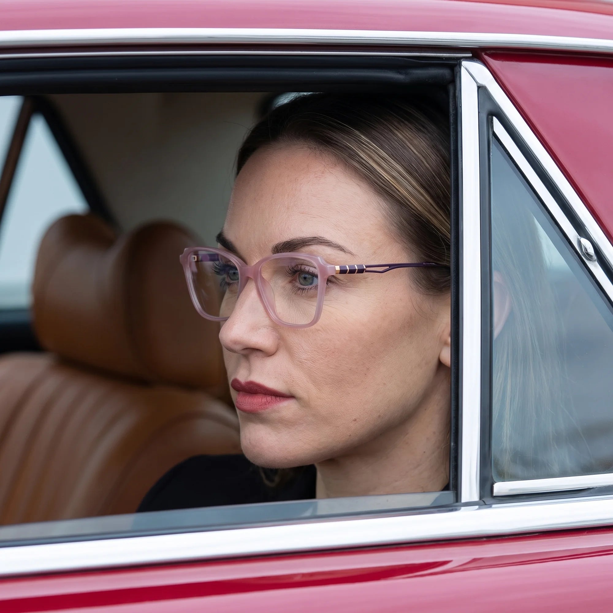 Fiore 1006 eyeglasses in pink, worn by a model – campaign portrait, gaze through a classic red car window