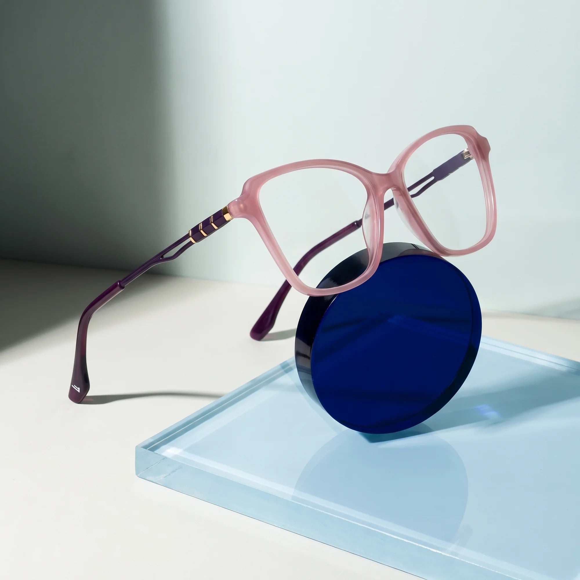 Fiore 1006 eyeglasses in pink – on a cobalt acrylic disc in soft daylight