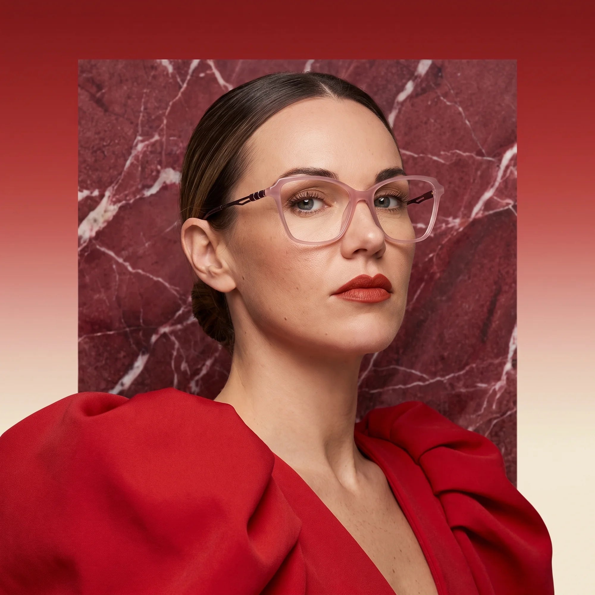 Fiore 1006 eyeglasses in pink, worn by a model – campaign portrait, red marble backdrop and draped scarlet dress