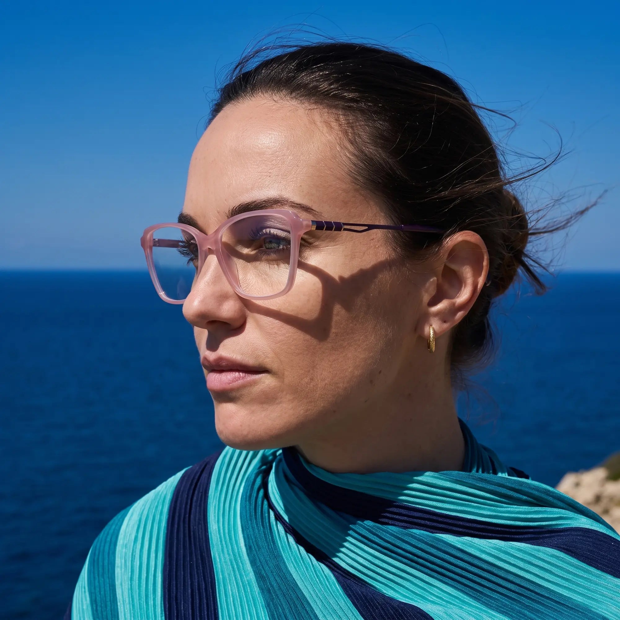 Fiore 1006 eyeglasses in pink, worn by a model – campaign portrait, windswept portrait over the deep blue sea