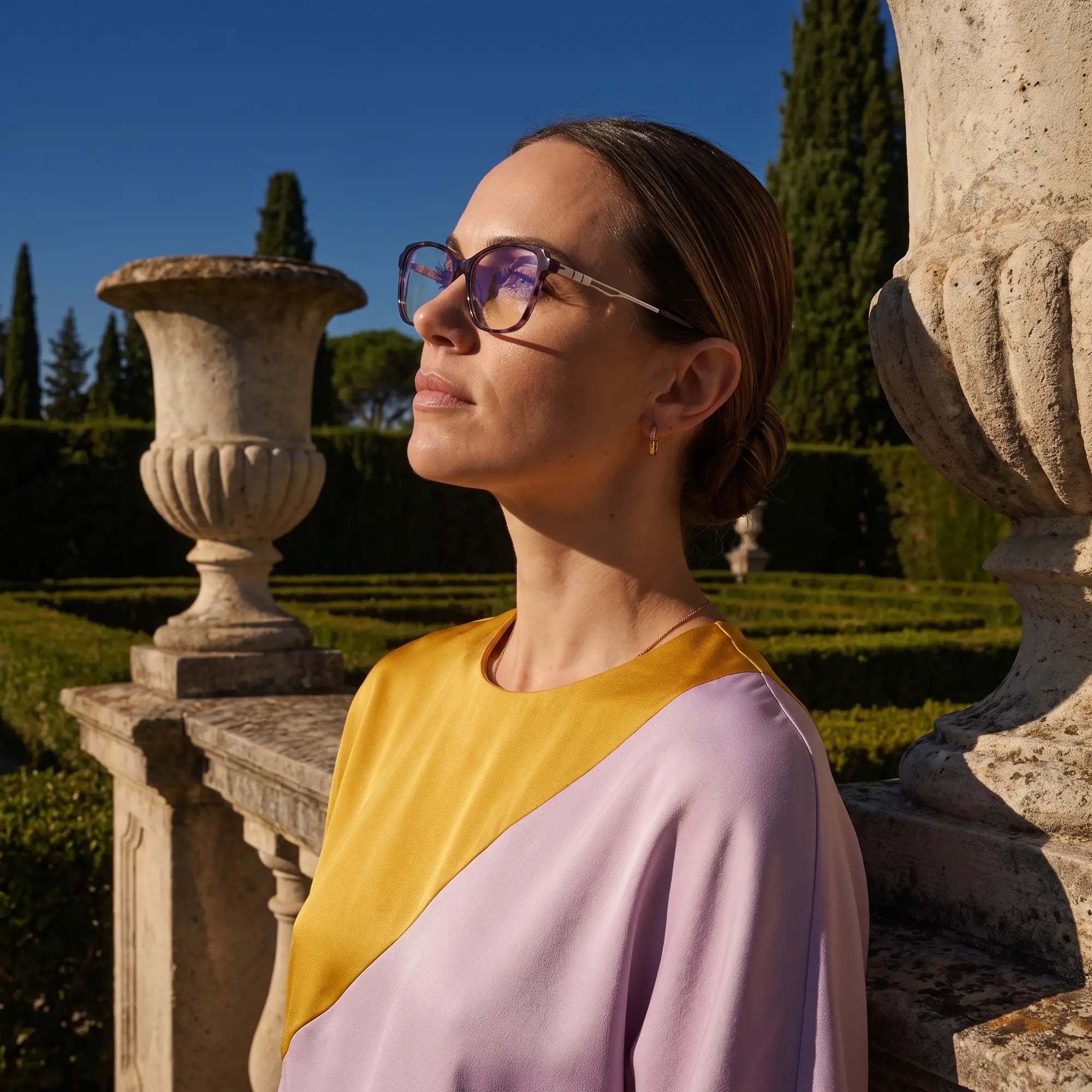 Fiore 1006 eyeglasses in purple, worn by a model – campaign portrait, dusk light over a cypress garden