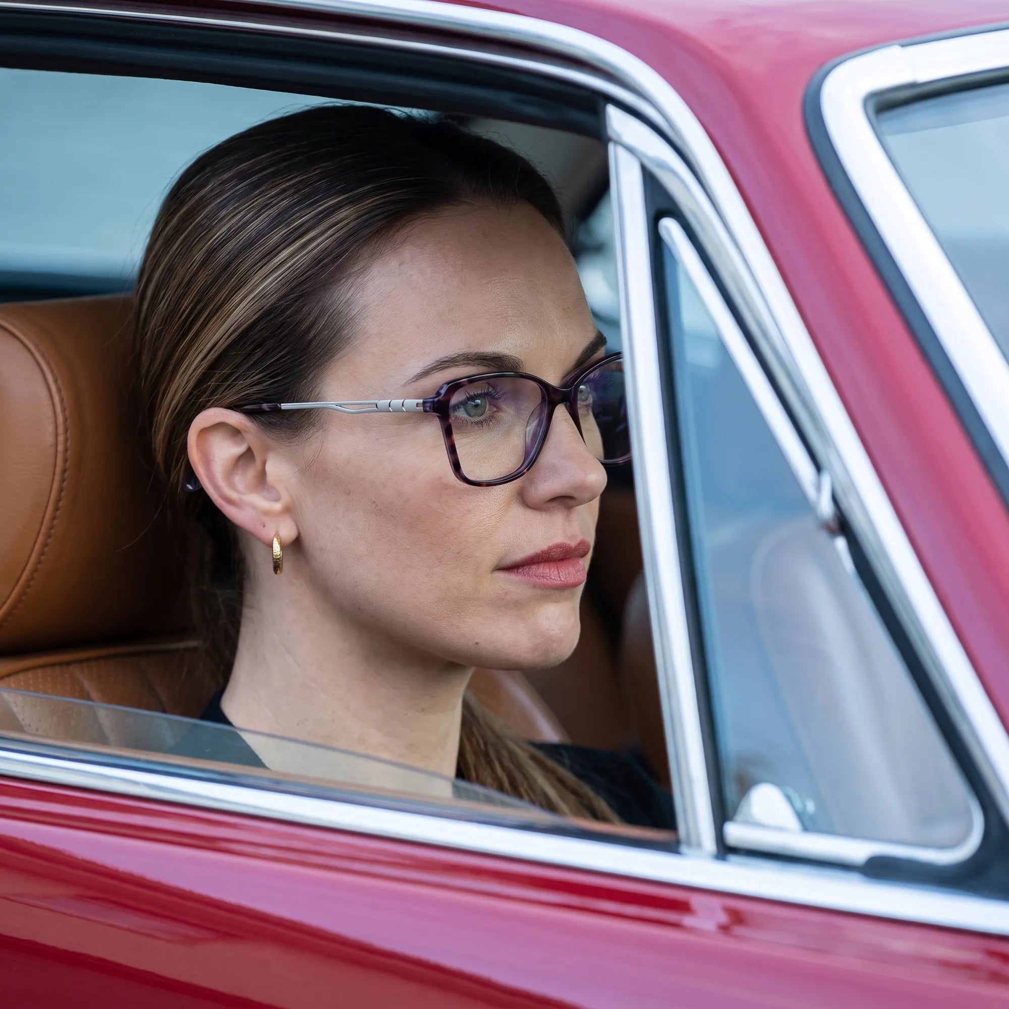 Fiore 1006 eyeglasses in purple, worn by a model – campaign portrait, gaze through a classic red car window