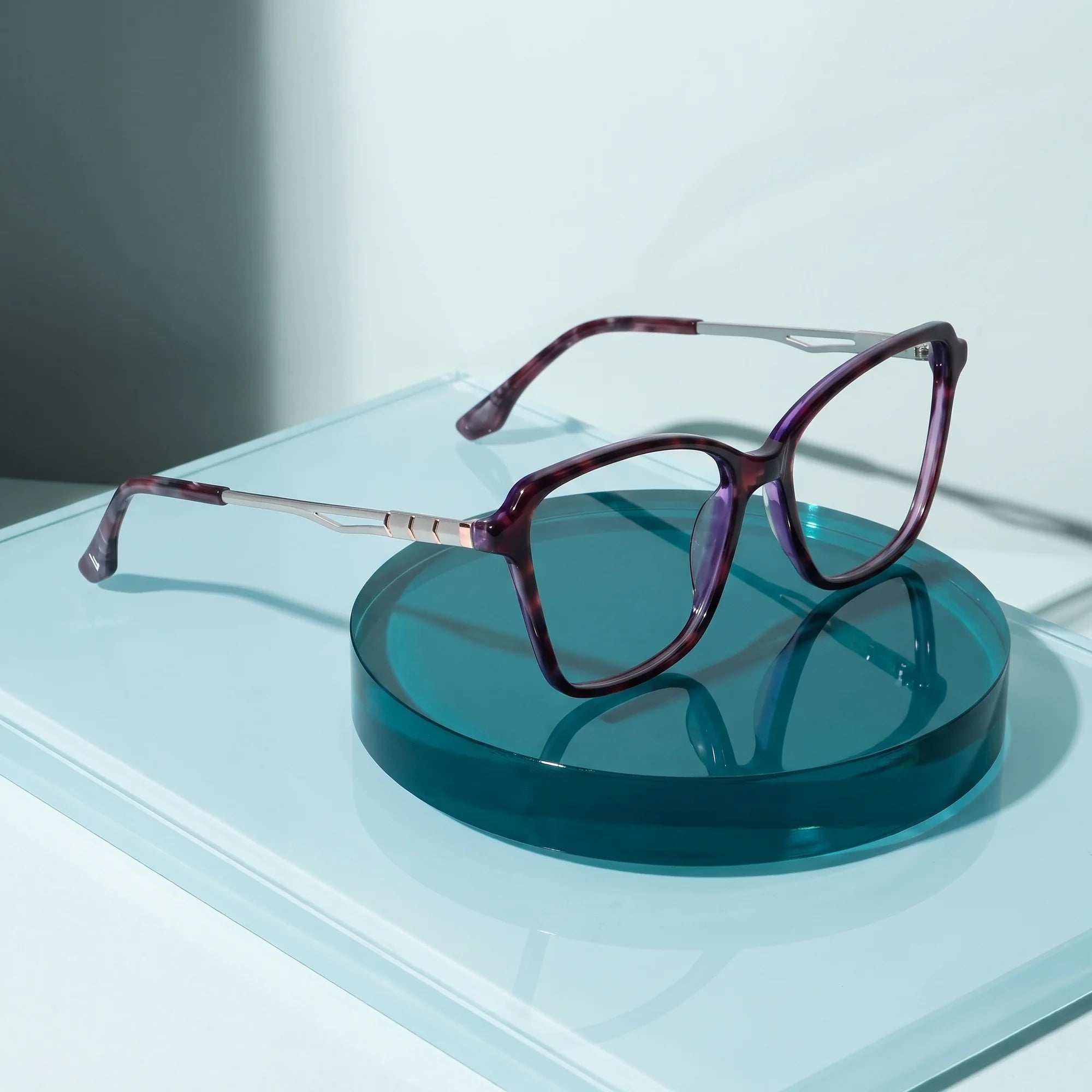 Fiore 1006 eyeglasses in purple – on a cobalt acrylic disc in soft daylight
