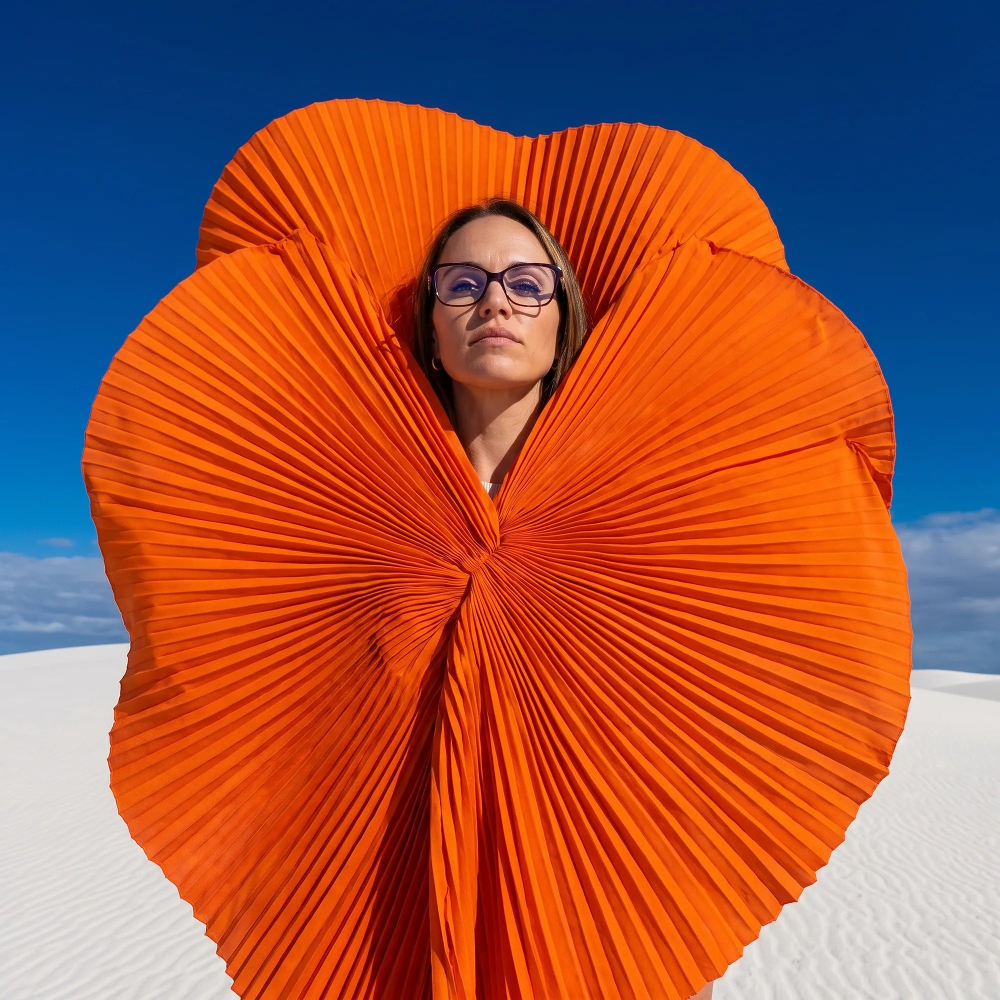 Fiore 1006 eyeglasses in purple, worn by a model – campaign portrait, sculptural orange pleated fan on white dunes