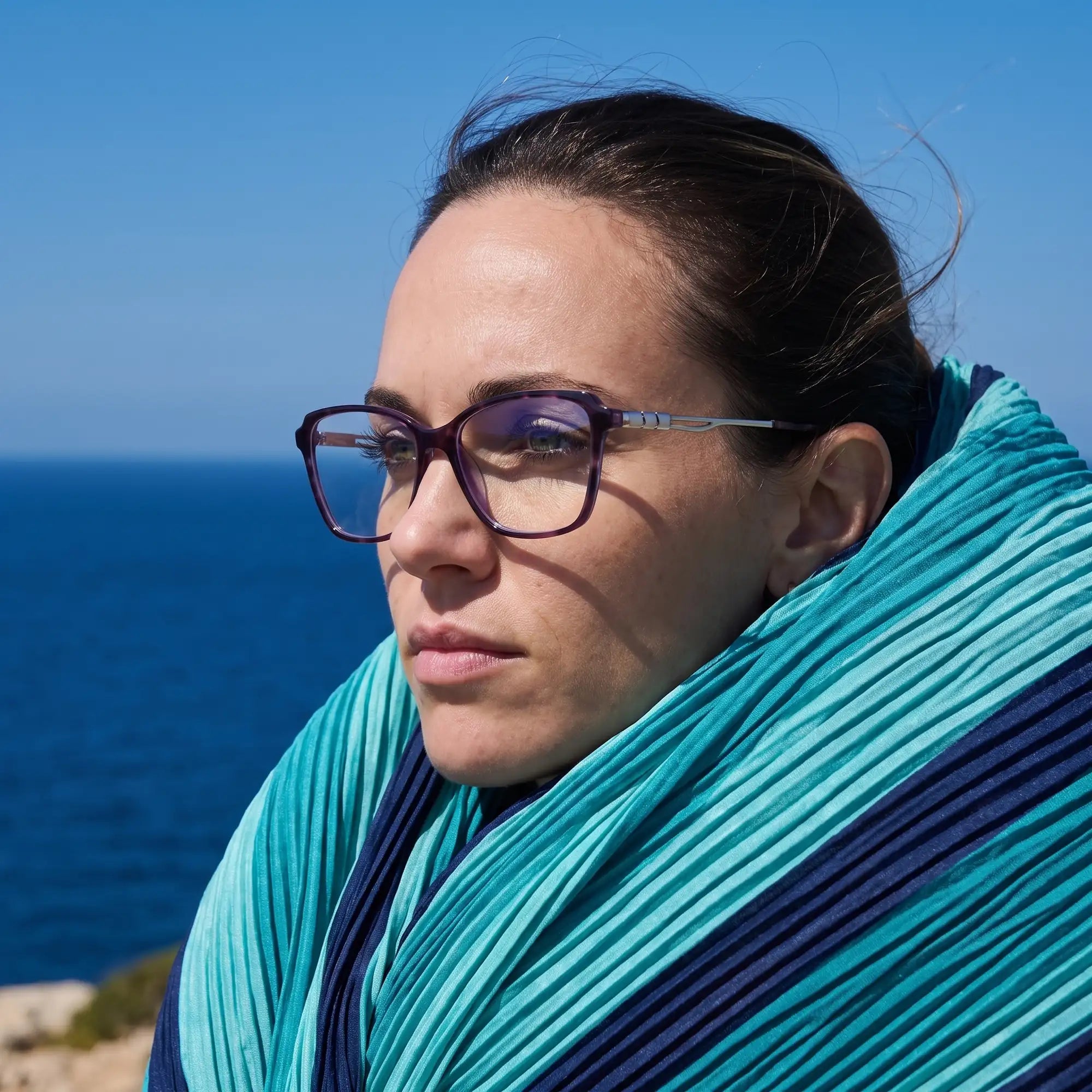 Fiore 1006 eyeglasses in purple, worn by a model – campaign portrait, windswept portrait over the deep blue sea
