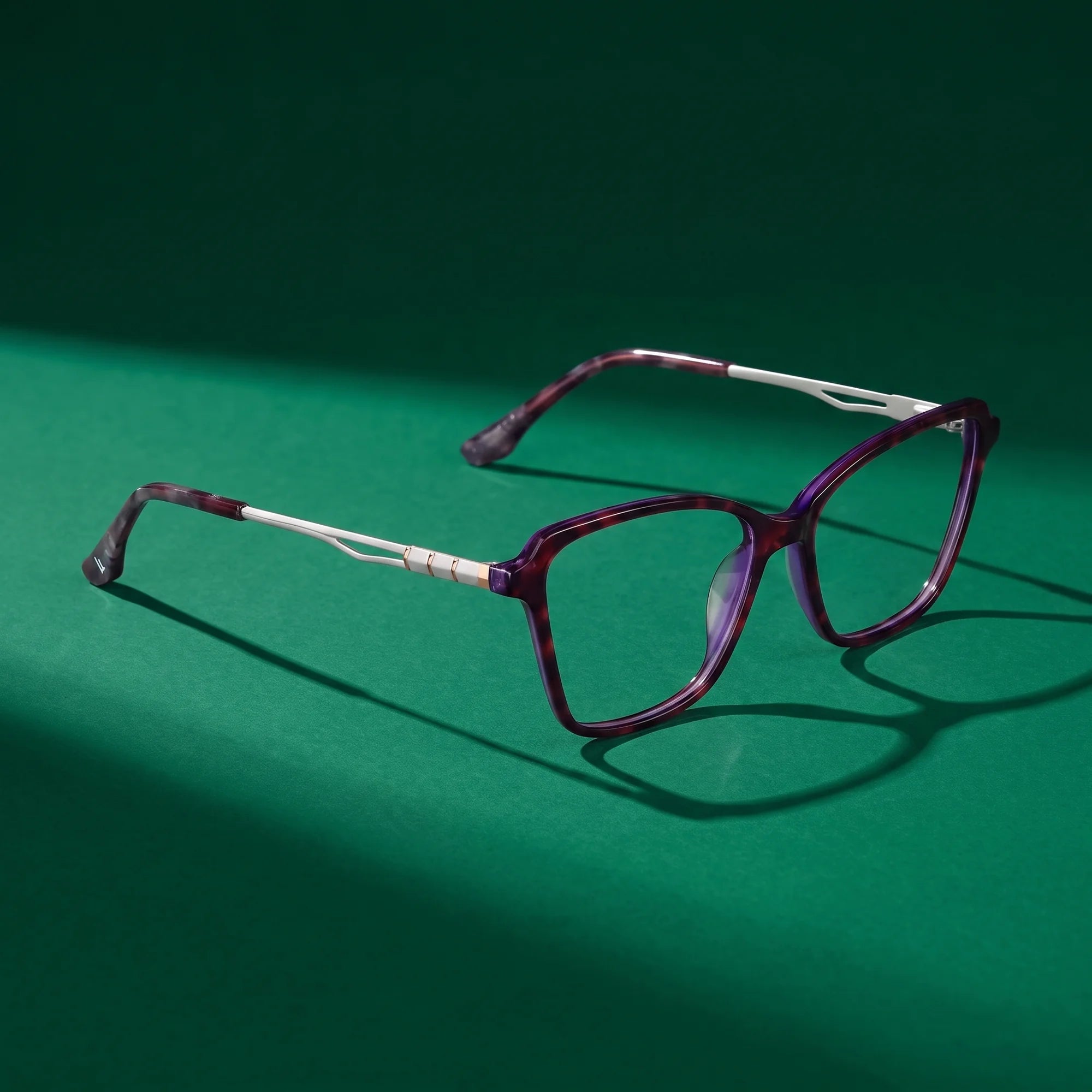 Fiore 1006 eyeglasses in purple – editorial still life on a saturated emerald set