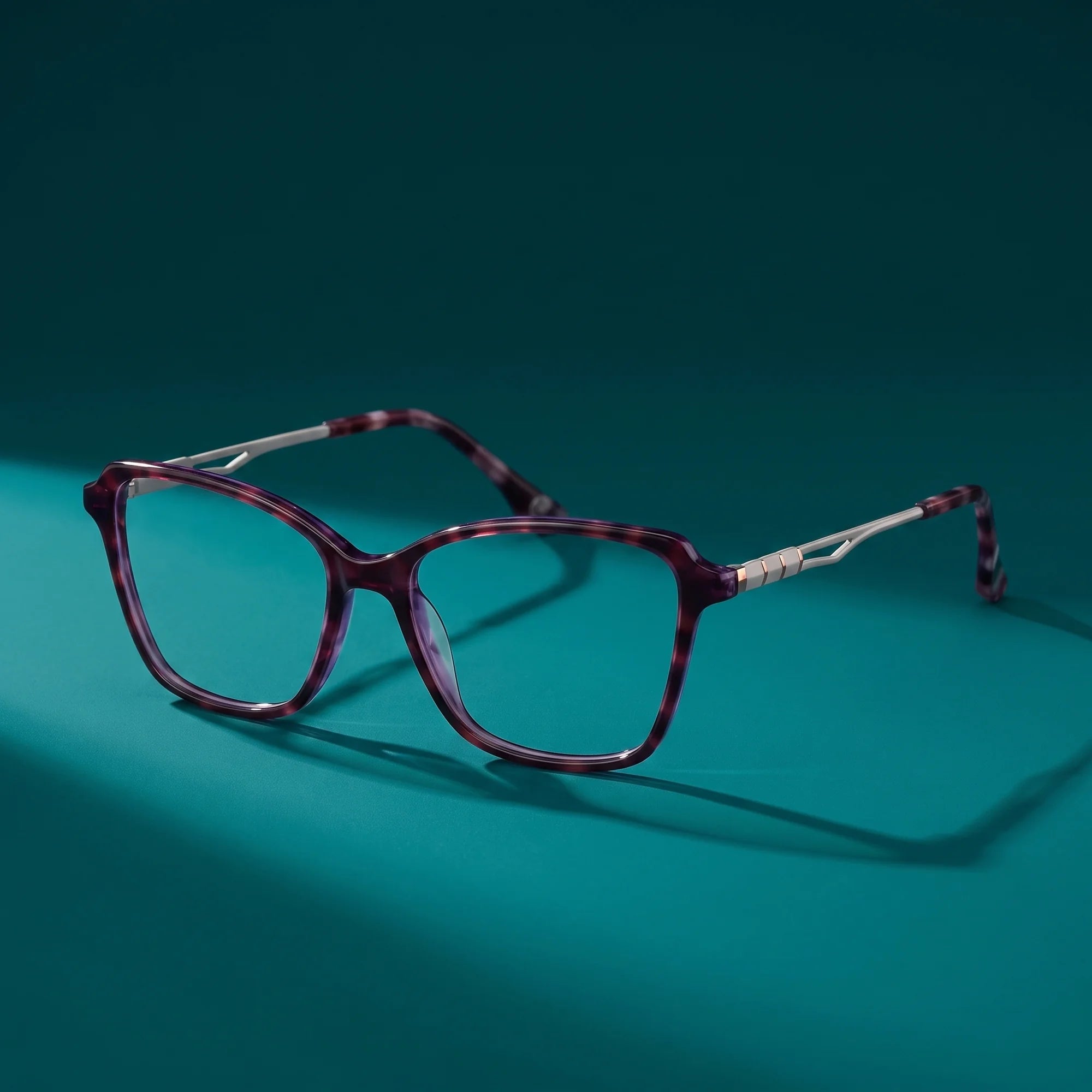 Fiore 1006 eyeglasses in purple – still life on a seamless teal studio backdrop