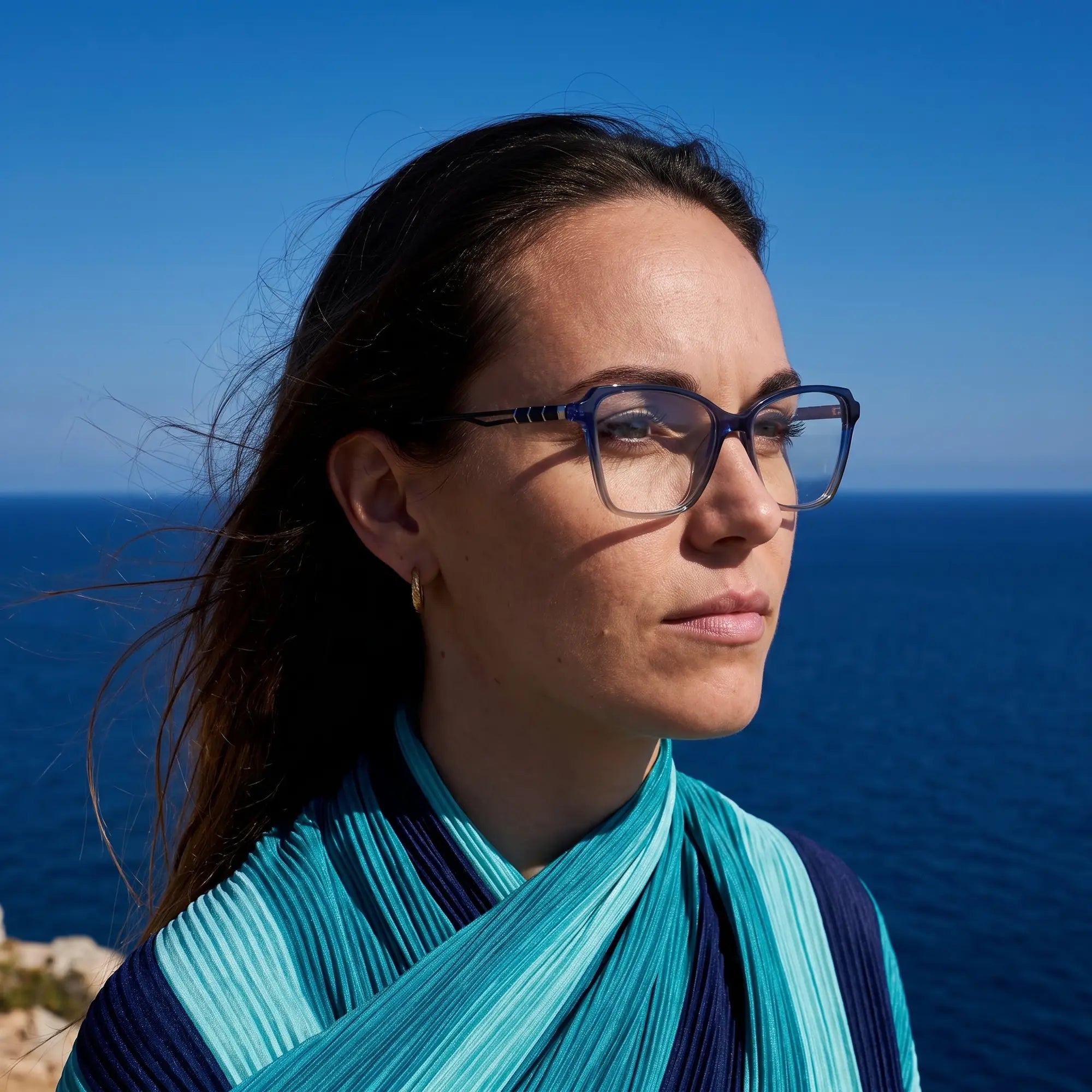 Fiore 1006 eyeglasses in blue, worn by a model – campaign portrait, windswept portrait over the deep blue sea