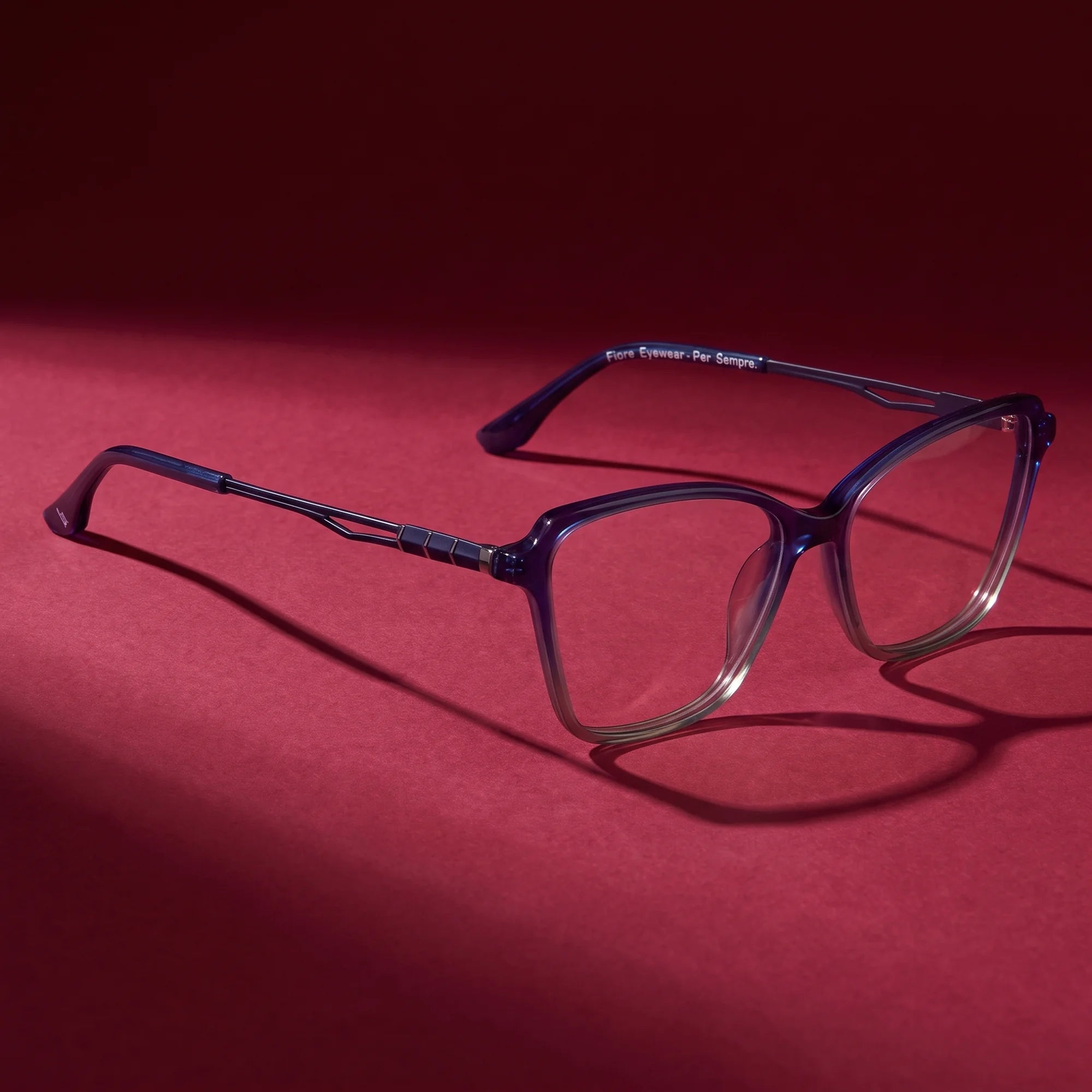 Fiore 1006 eyeglasses in blue – editorial still life on a saturated burgundy set