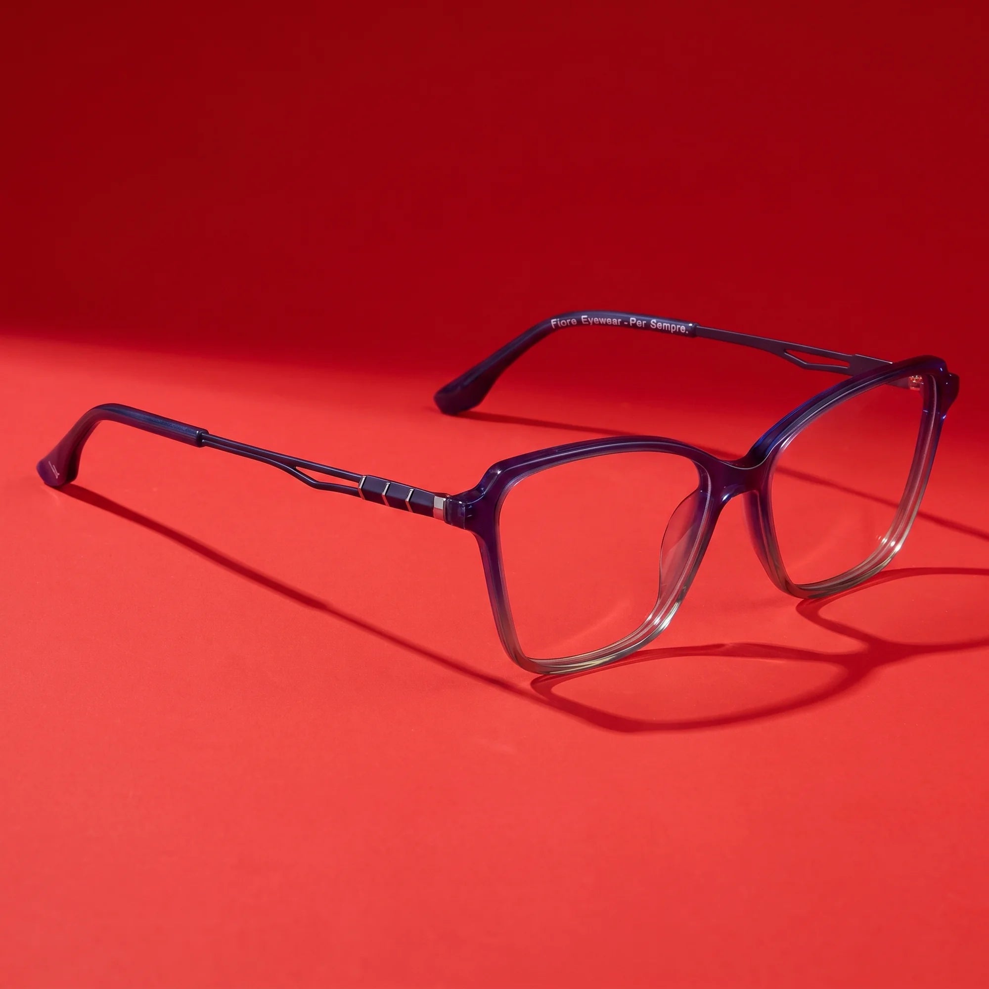Fiore 1006 eyeglasses in blue – hero still life against a deep vivid red backdrop