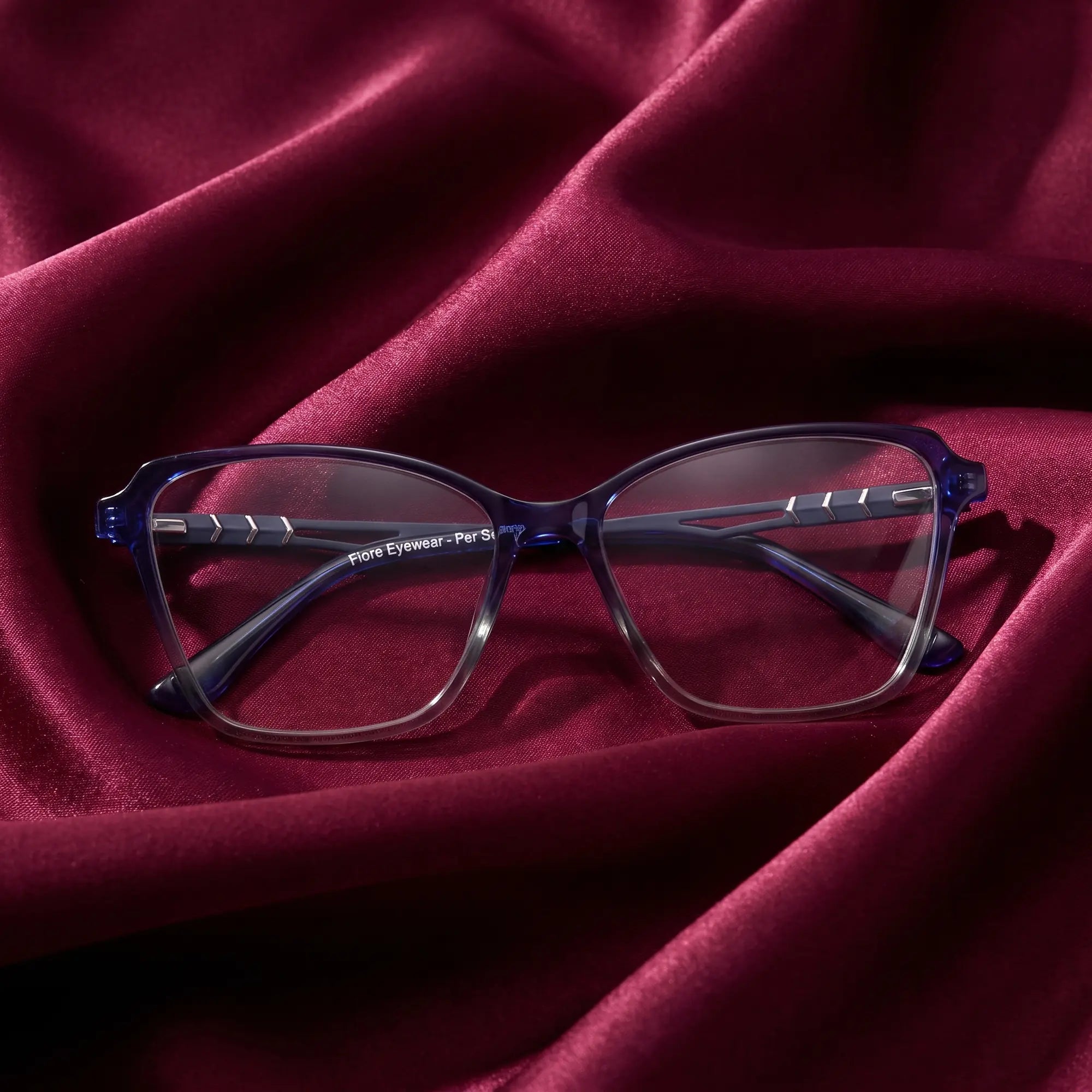 Fiore 1006 eyeglasses in blue – nested in flowing burgundy silk