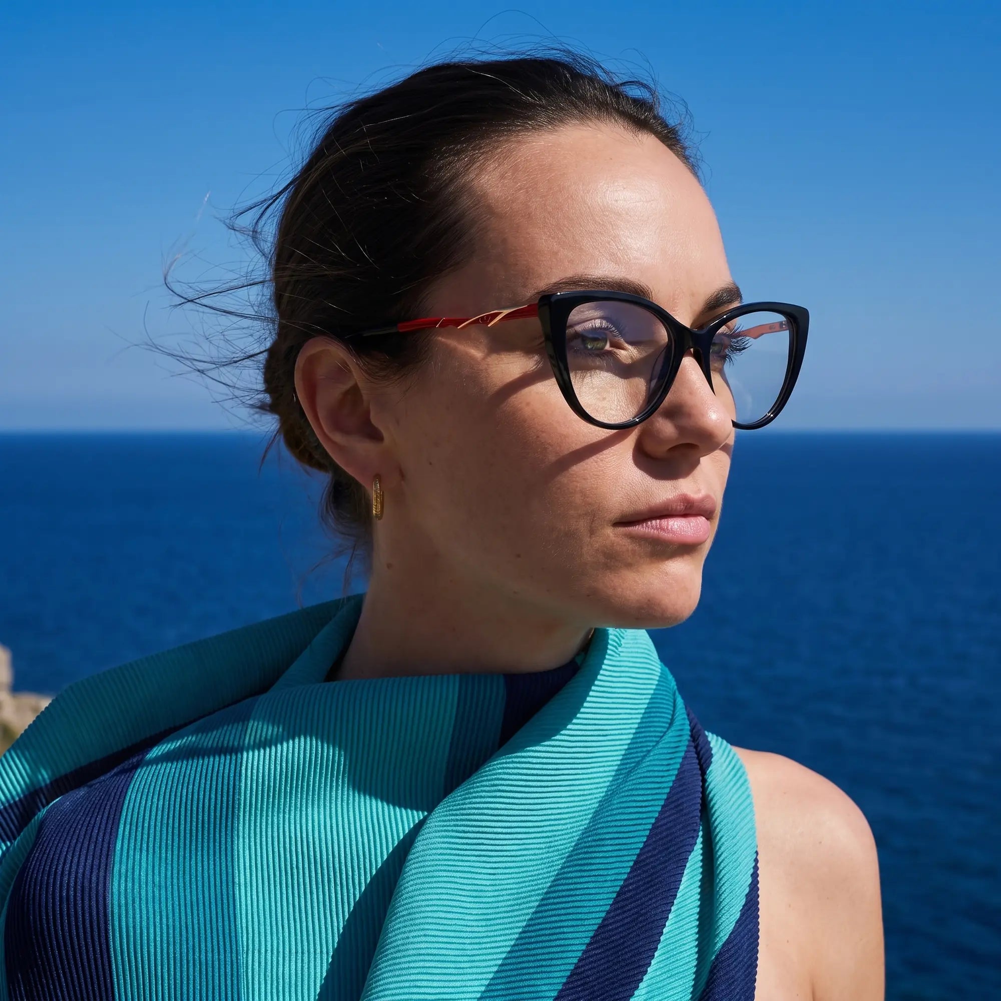 Fiore 1010 eyeglasses in black, worn by a model – campaign portrait, windswept portrait over the deep blue sea