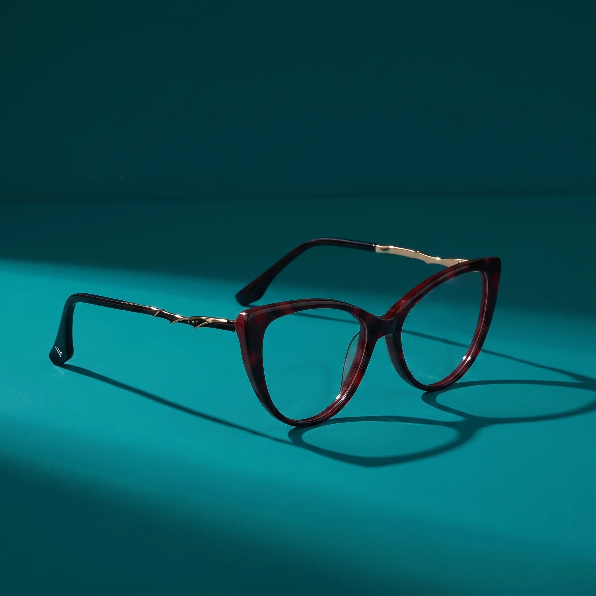 Fiore 1010 eyeglasses in red – hero still life against a deep teal backdrop