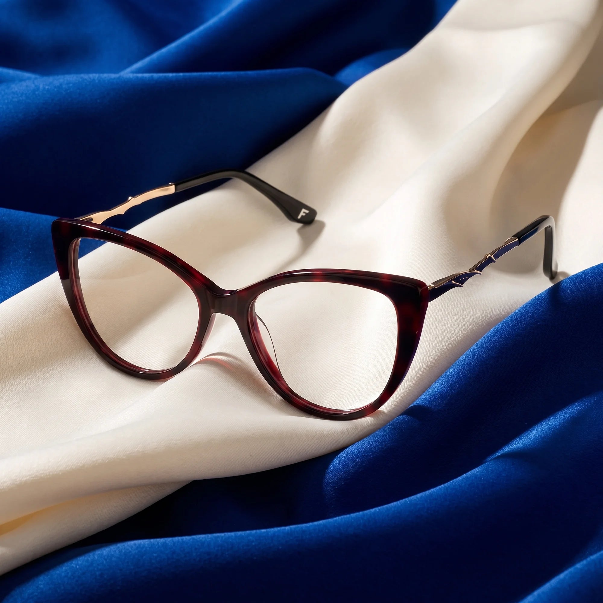 Fiore 1010 eyeglasses in red – resting on draped cobalt and ivory silk