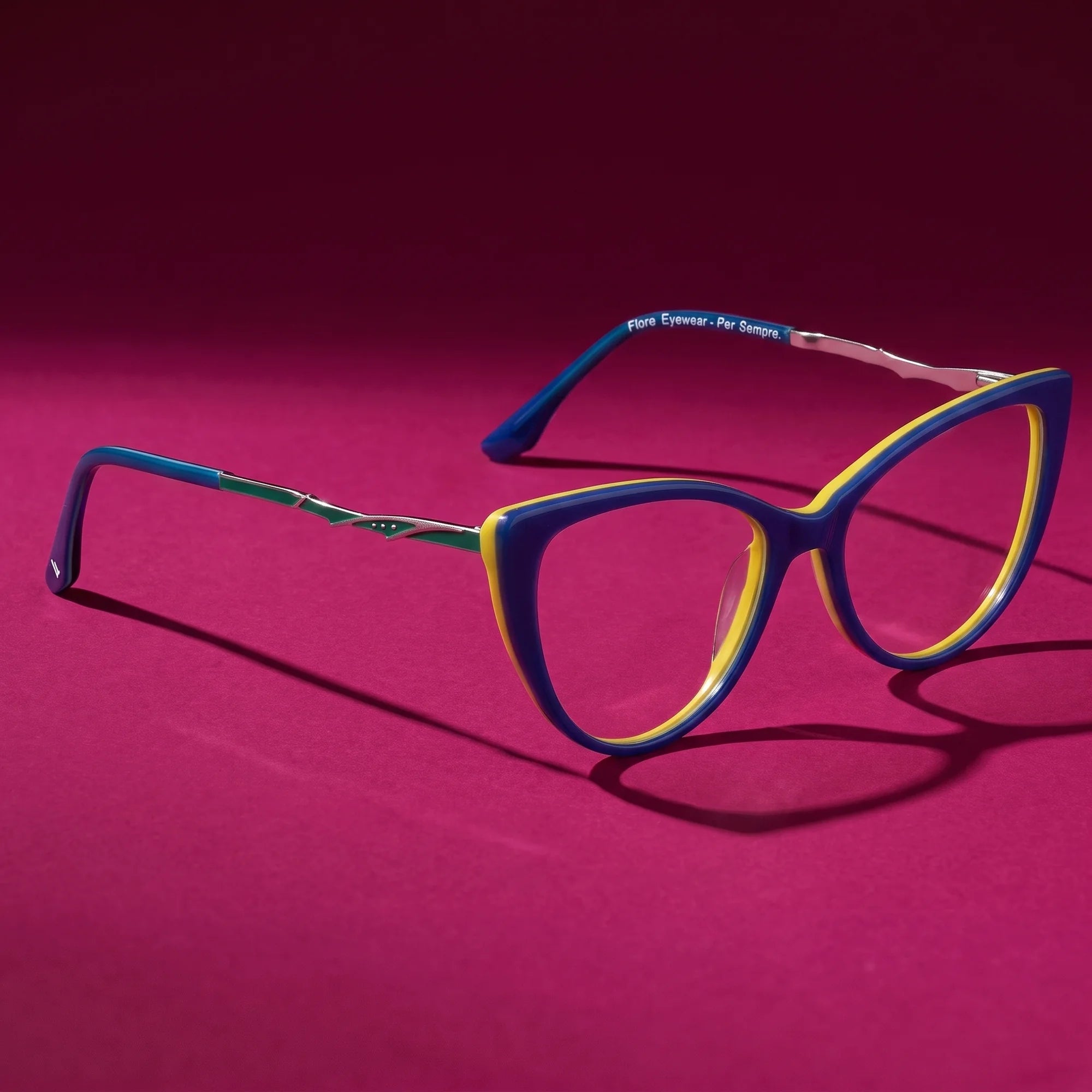 Fiore 1010 eyeglasses in blue green – hero still life against a deep magenta backdrop