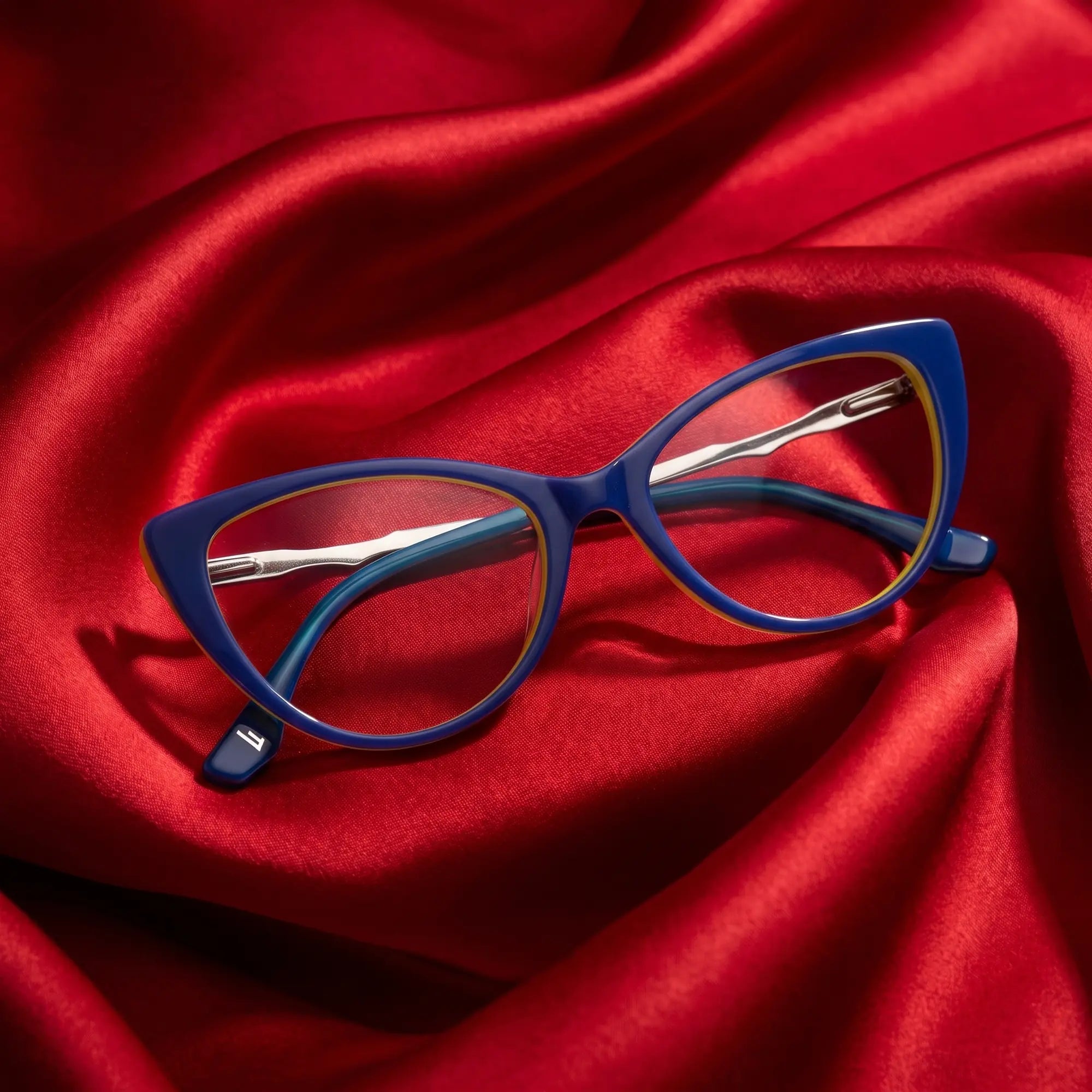 Fiore 1010 eyeglasses in blue green – nested in flowing vivid red silk