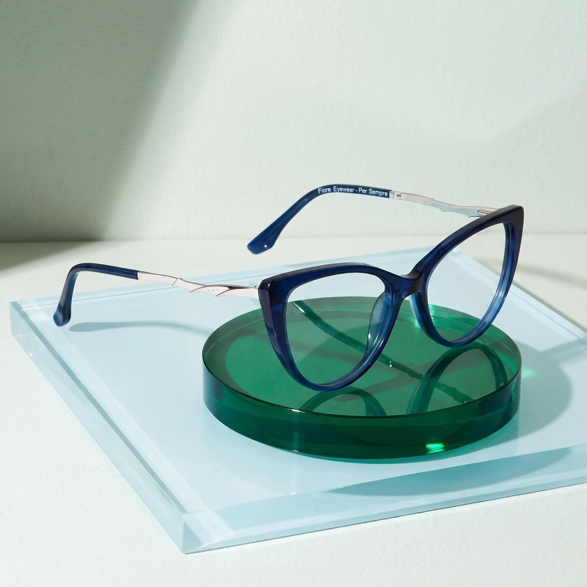 Fiore 1010 eyeglasses in blue – on a cobalt acrylic disc in soft daylight