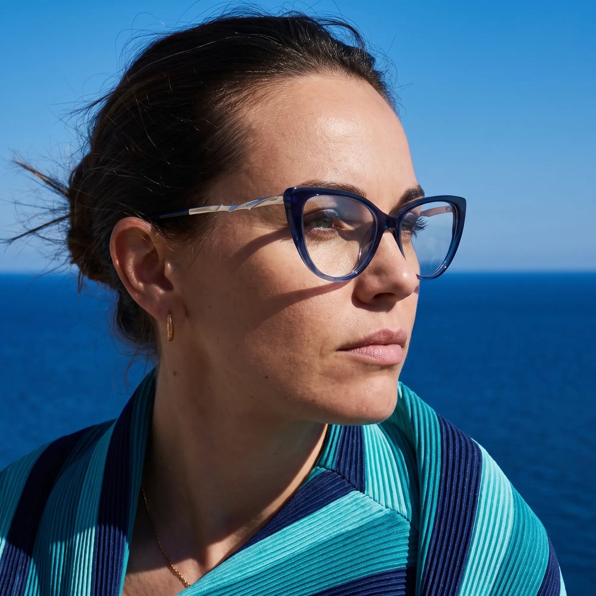 Fiore 1010 eyeglasses in blue, worn by a model – campaign portrait, windswept portrait over the deep blue sea