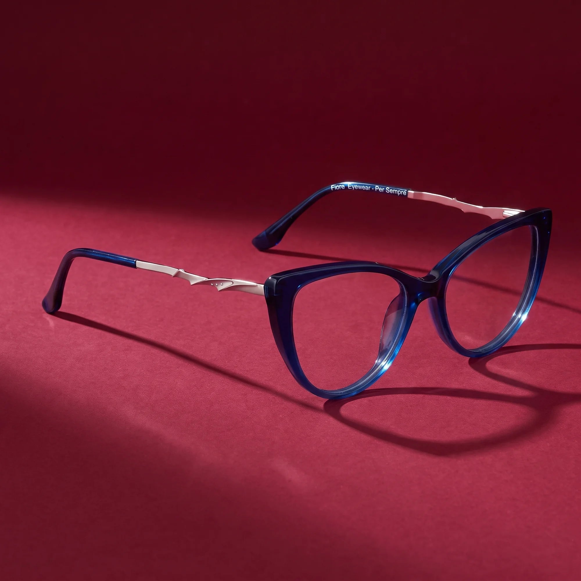 Fiore 1010 eyeglasses in blue – editorial still life on a saturated burgundy set