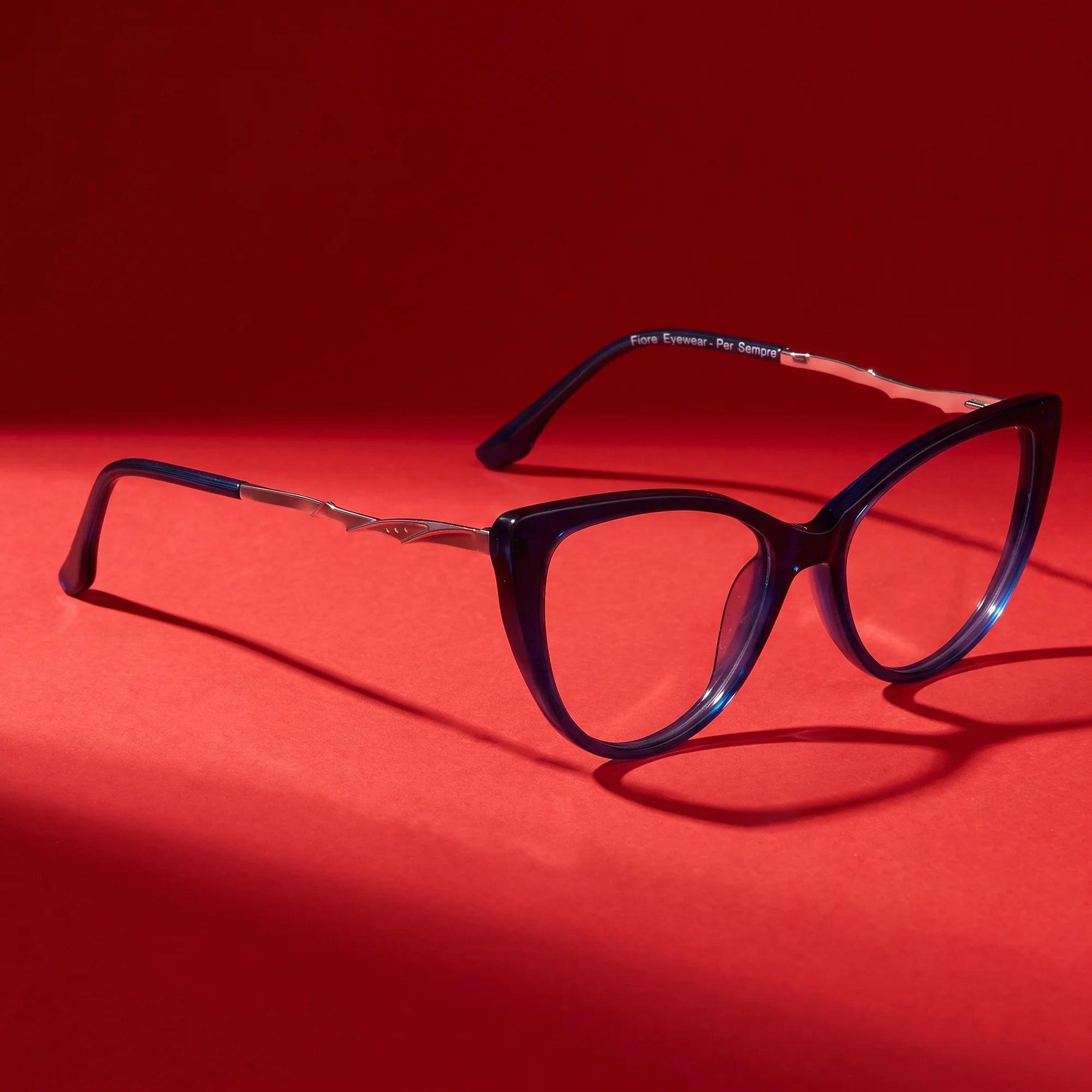 Fiore 1010 eyeglasses in blue – hero still life against a deep vivid red backdrop