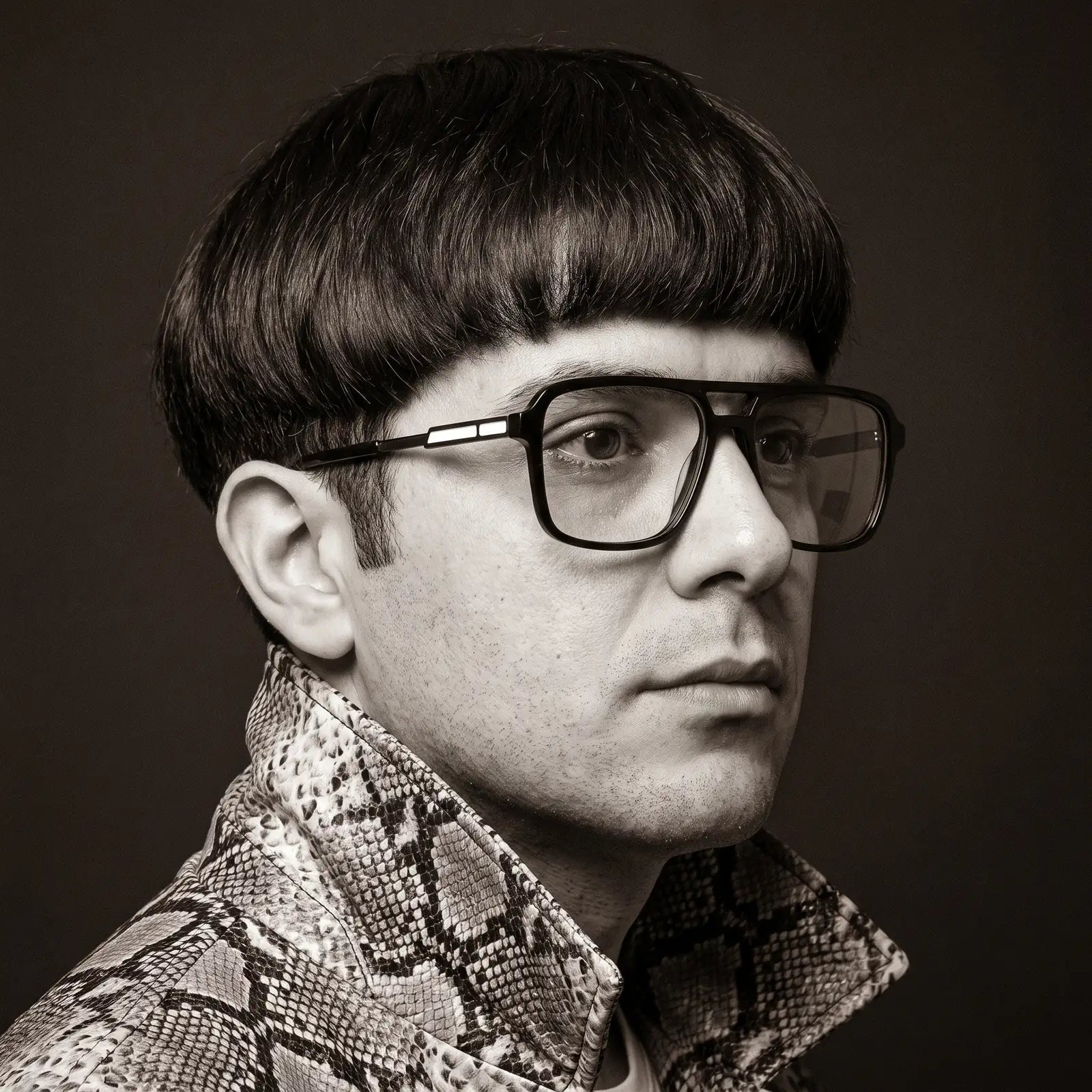 Fiore 1014 eyeglasses in black, worn by a model – campaign portrait, monochrome studio portrait, red graphic accents