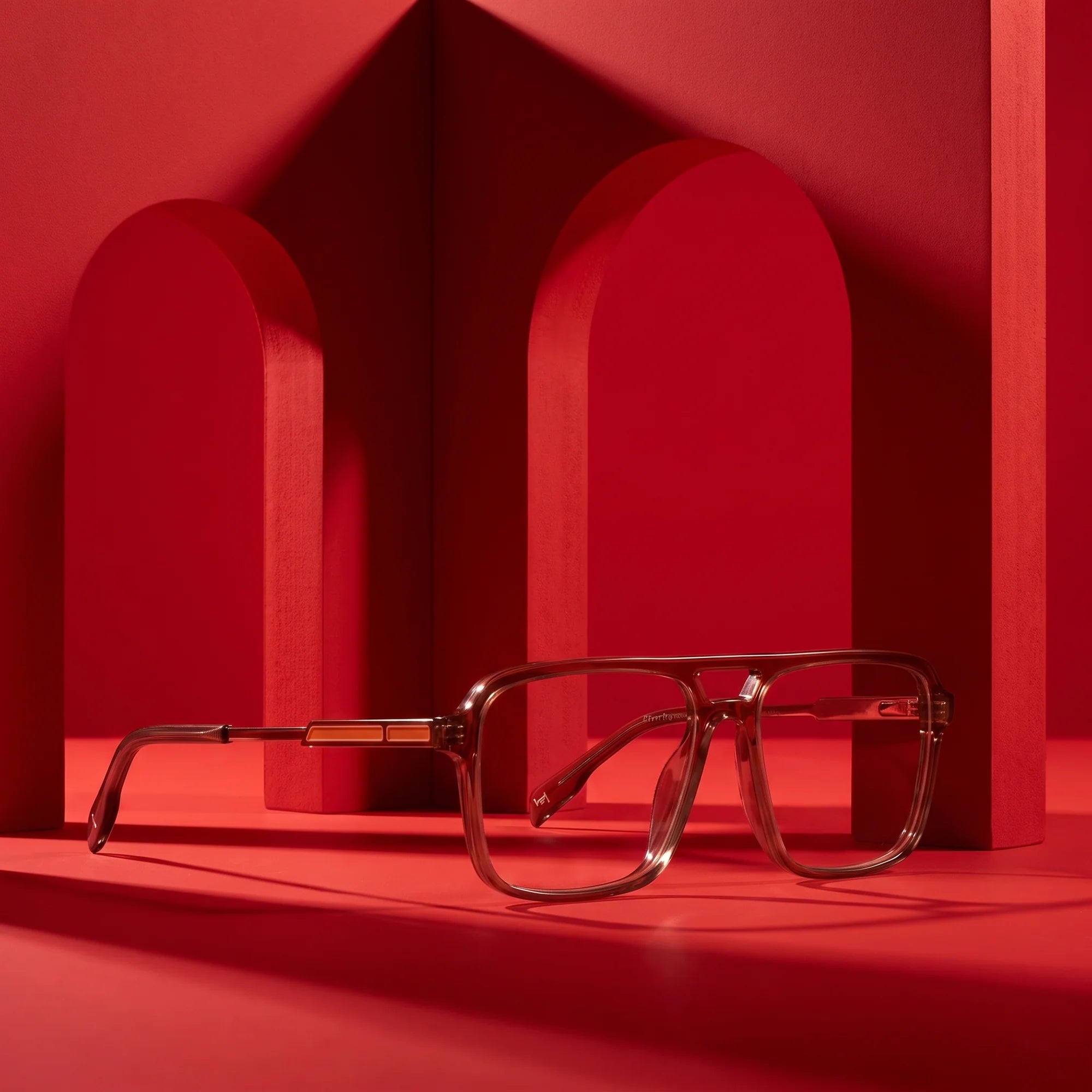 Fiore 1014 eyeglasses in brown – displayed on a vivid red podium among arches