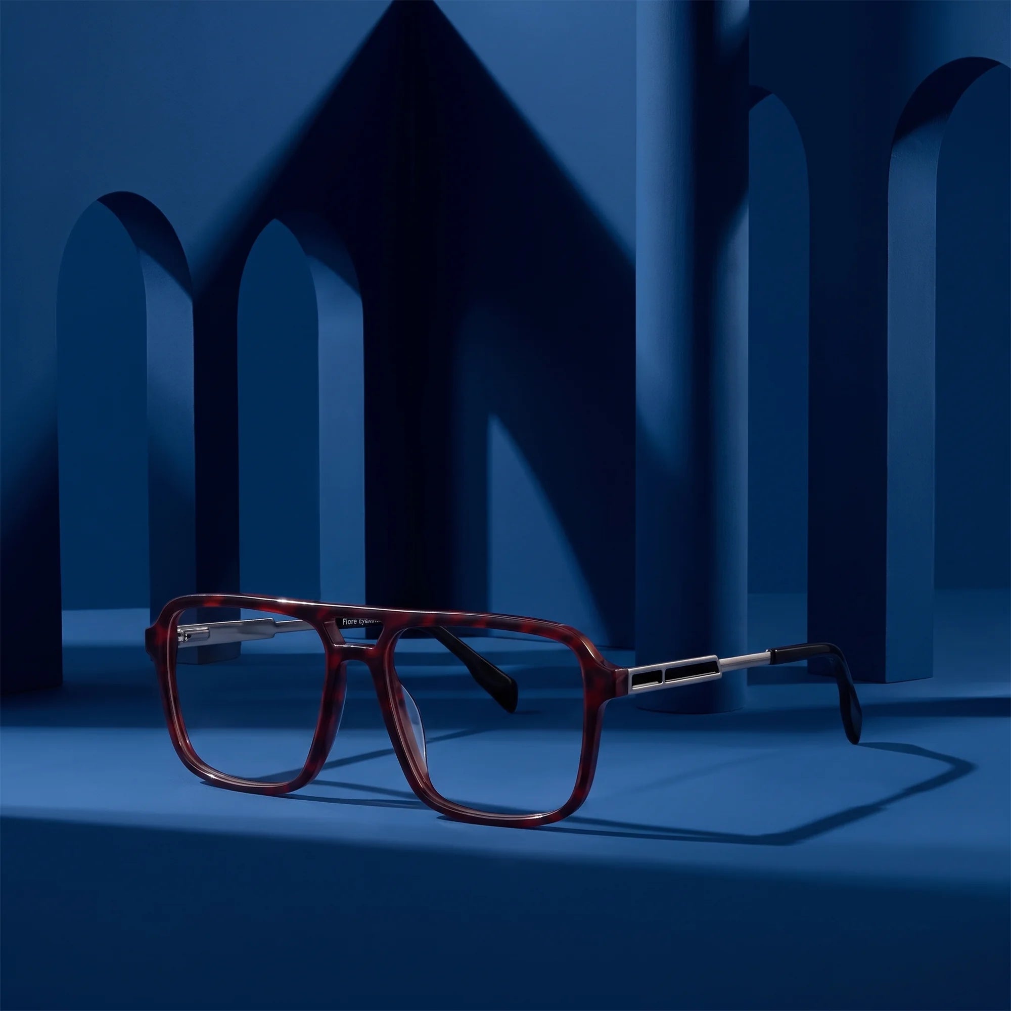 Fiore 1014 eyeglasses in tortoiseshell – displayed on a midnight blue podium among arches