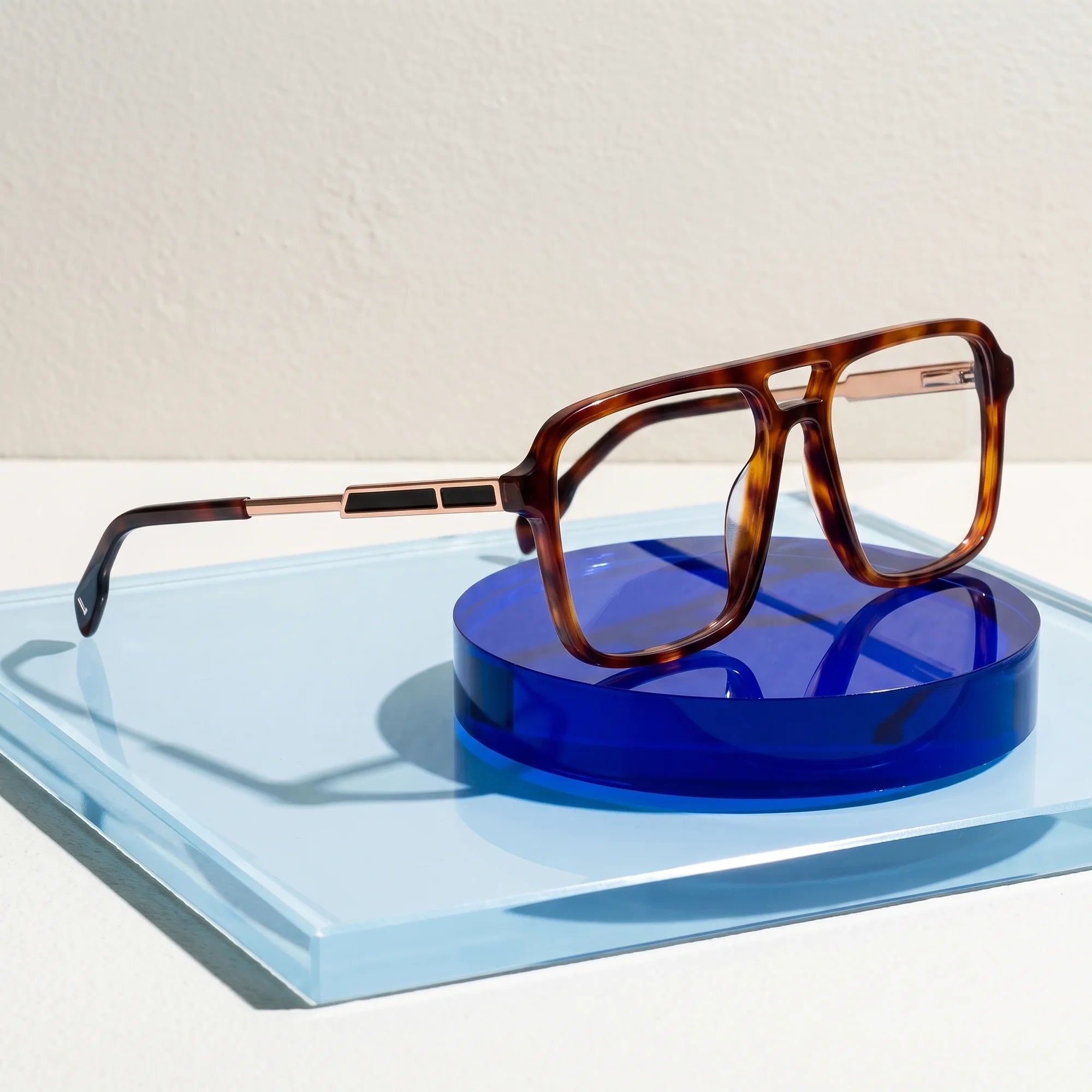 Fiore 1014 eyeglasses in brown tortoiseshell – on a cobalt acrylic disc in soft daylight