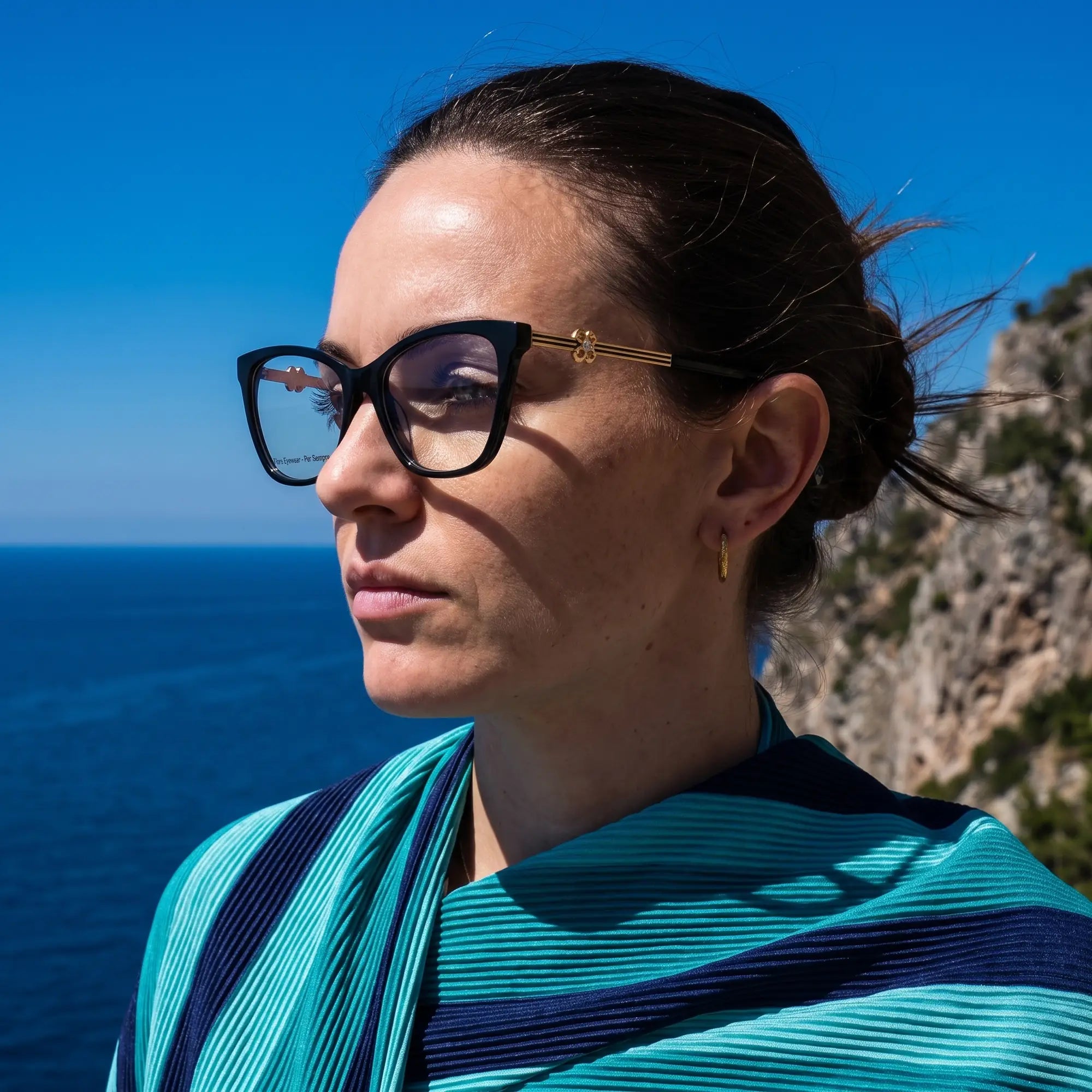 Fiore 10172 eyeglasses in black, worn by a model – campaign portrait, windswept portrait over the deep blue sea