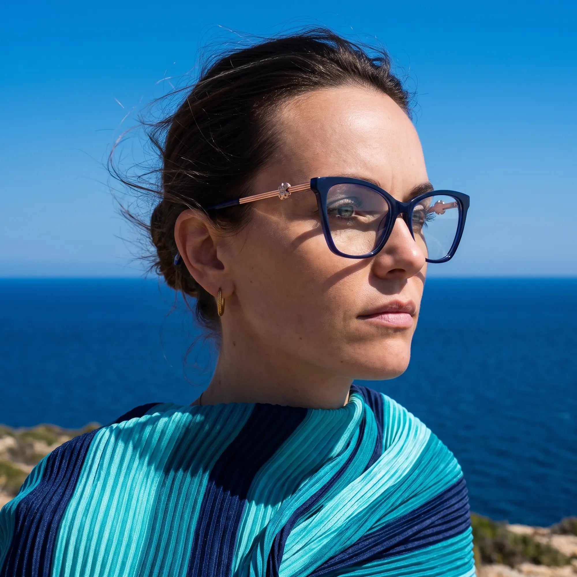 Fiore 10172 eyeglasses in blue, worn by a model – campaign portrait, windswept portrait over the deep blue sea