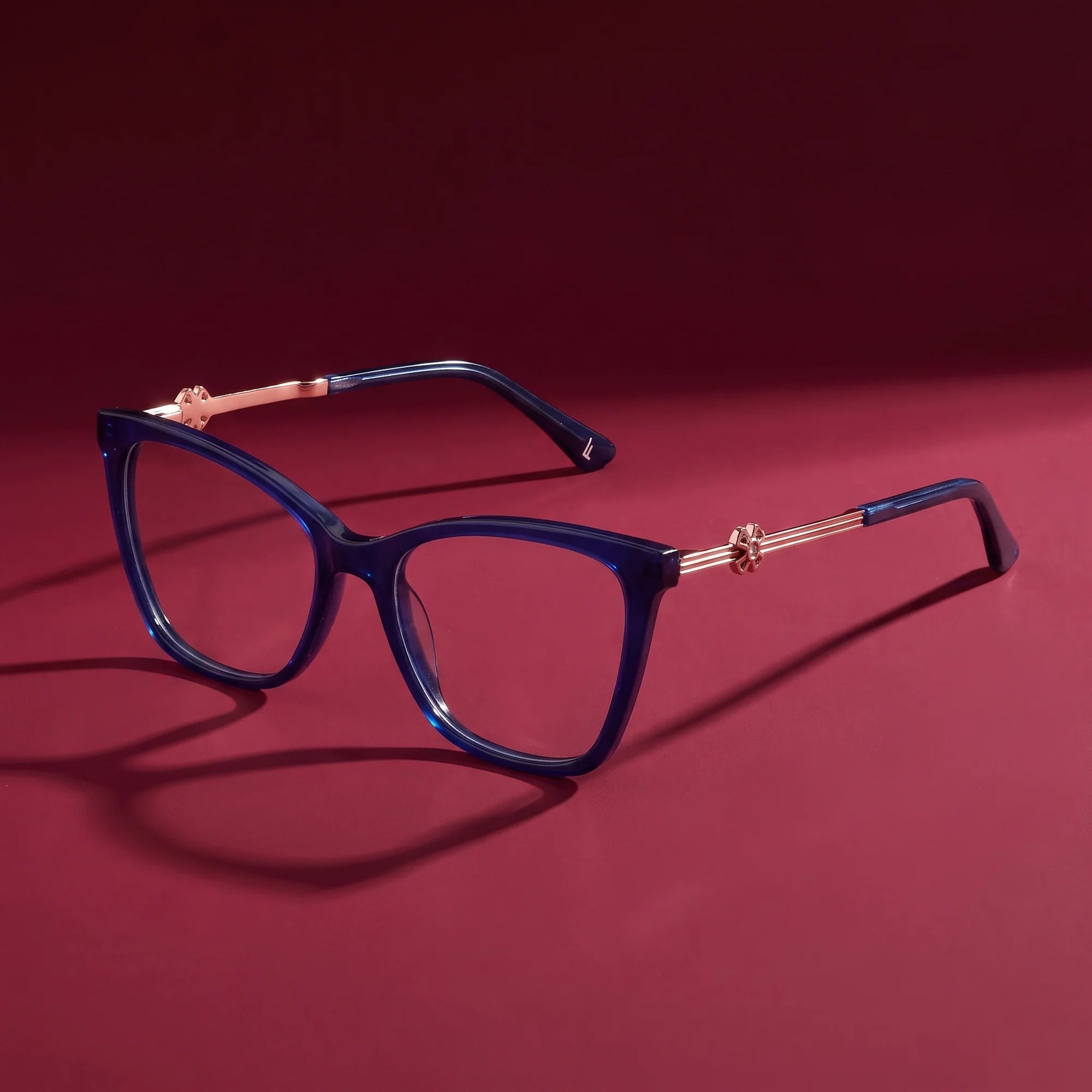 Fiore 10172 eyeglasses in blue – hero still life against a deep burgundy backdrop