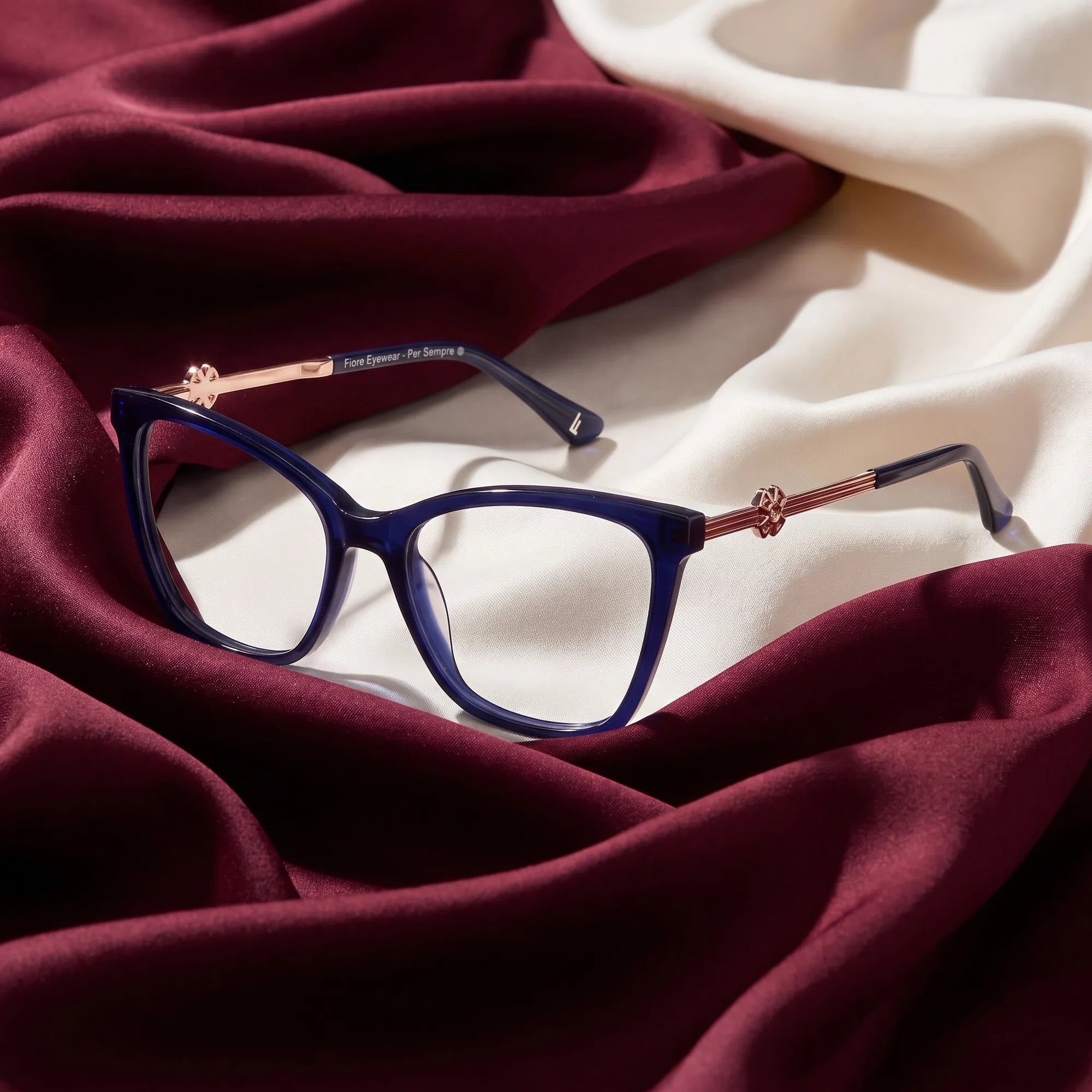 Fiore 10172 eyeglasses in blue – resting on draped burgundy and ivory silk
