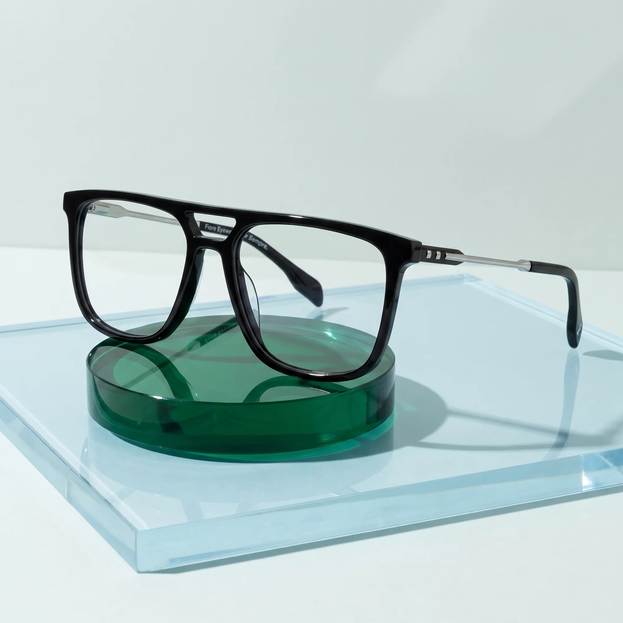 Fiore 10177 eyeglasses in black – on a cobalt acrylic disc in soft daylight