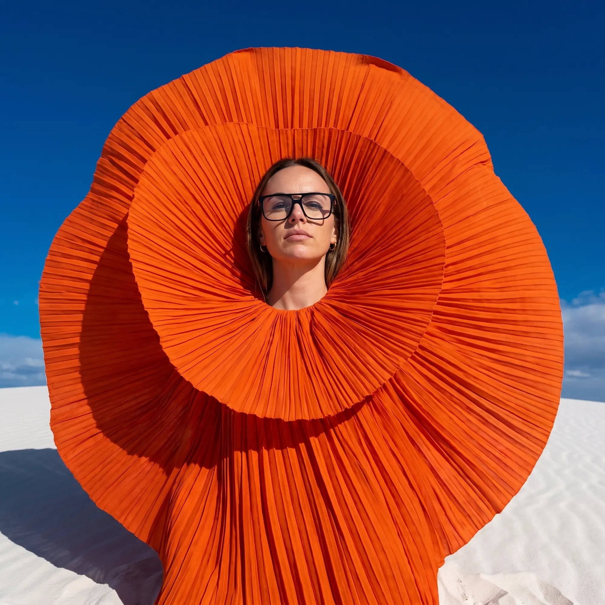 Fiore 10177 eyeglasses in black, worn by a model – campaign portrait, sculptural orange pleated fan on white dunes