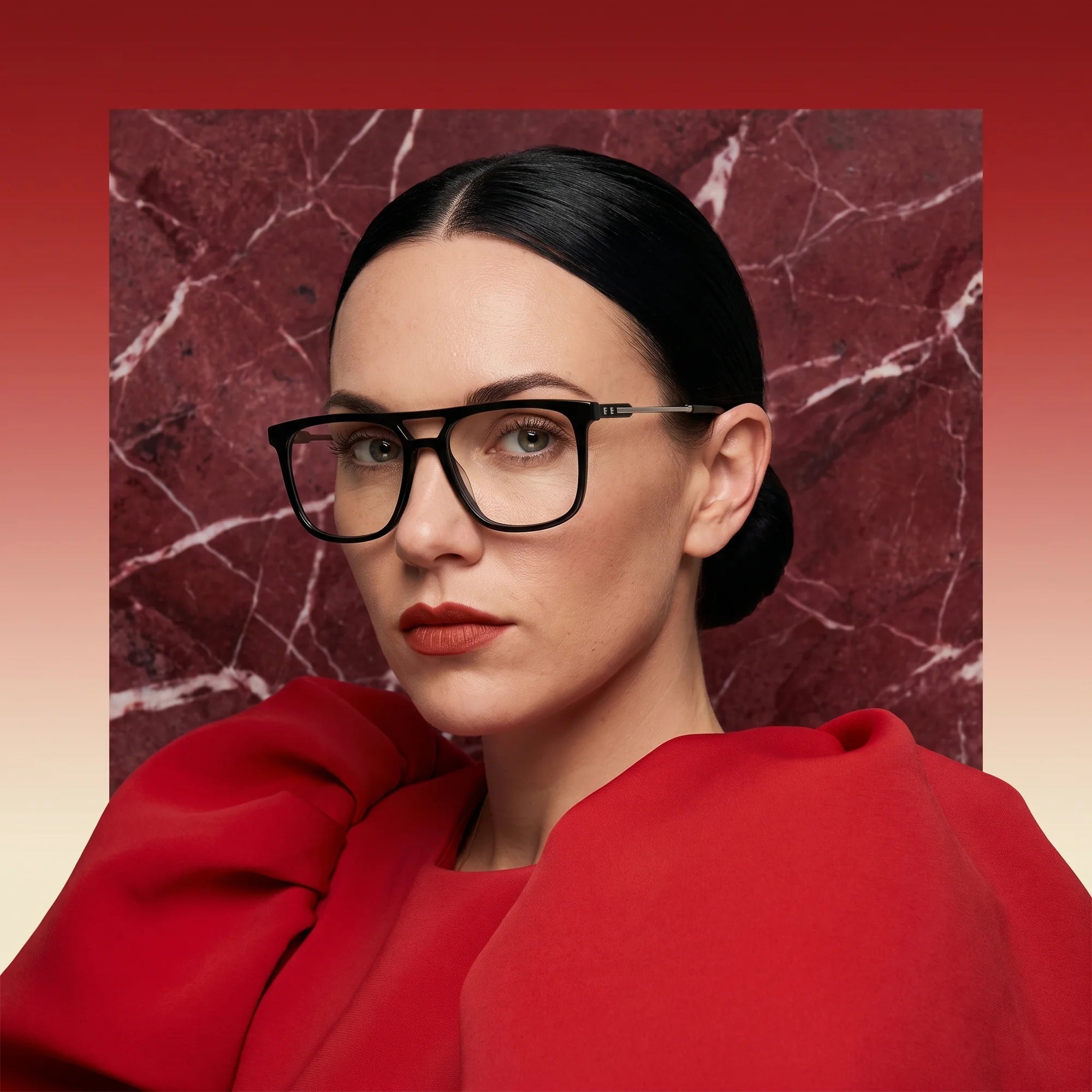Fiore 10177 eyeglasses in black, worn by a model – campaign portrait, red marble backdrop and draped scarlet dress