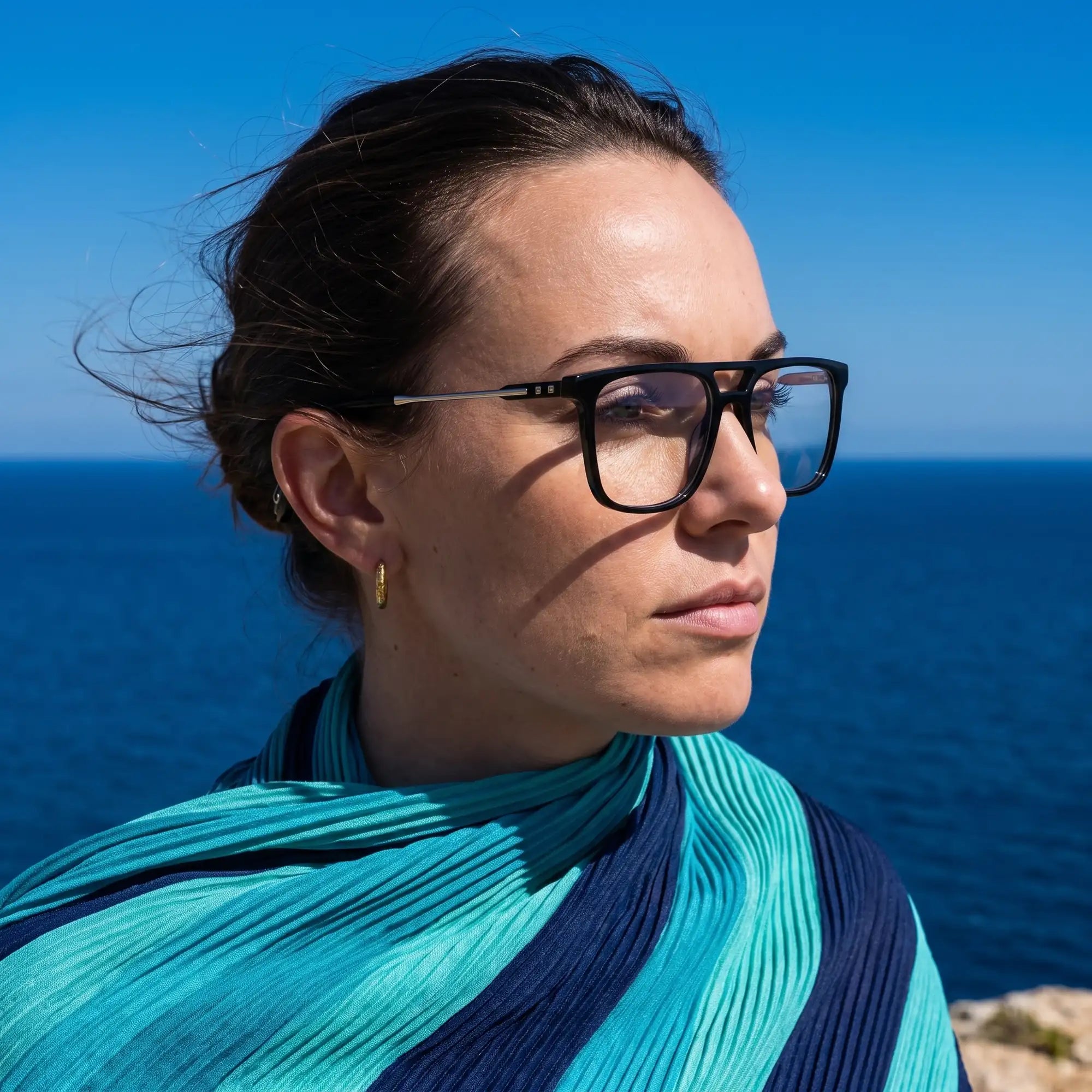 Fiore 10177 eyeglasses in black, worn by a model – campaign portrait, windswept portrait over the deep blue sea