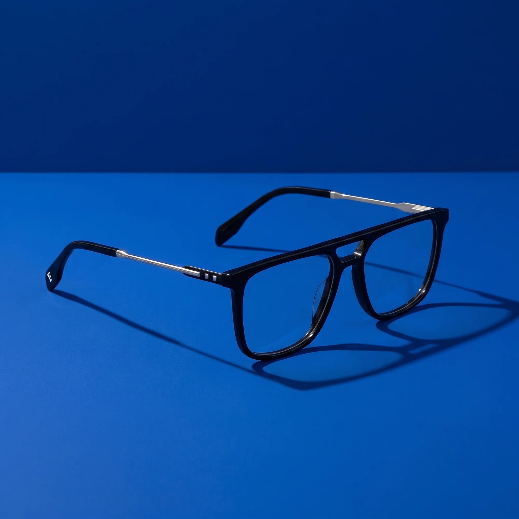 Fiore 10177 eyeglasses in black – hero still life against a deep cobalt backdrop