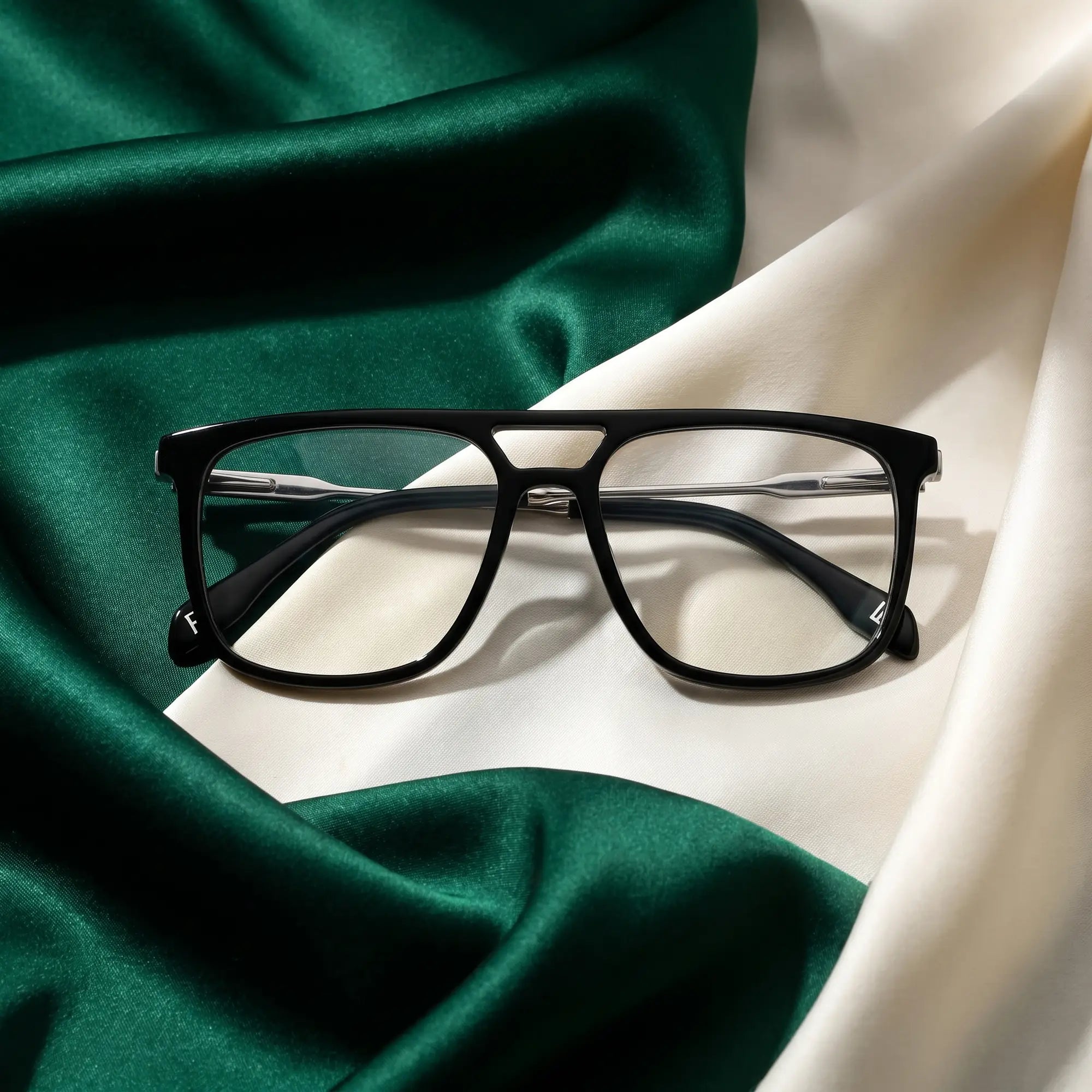 Fiore 10177 eyeglasses in black – resting on draped emerald and ivory silk