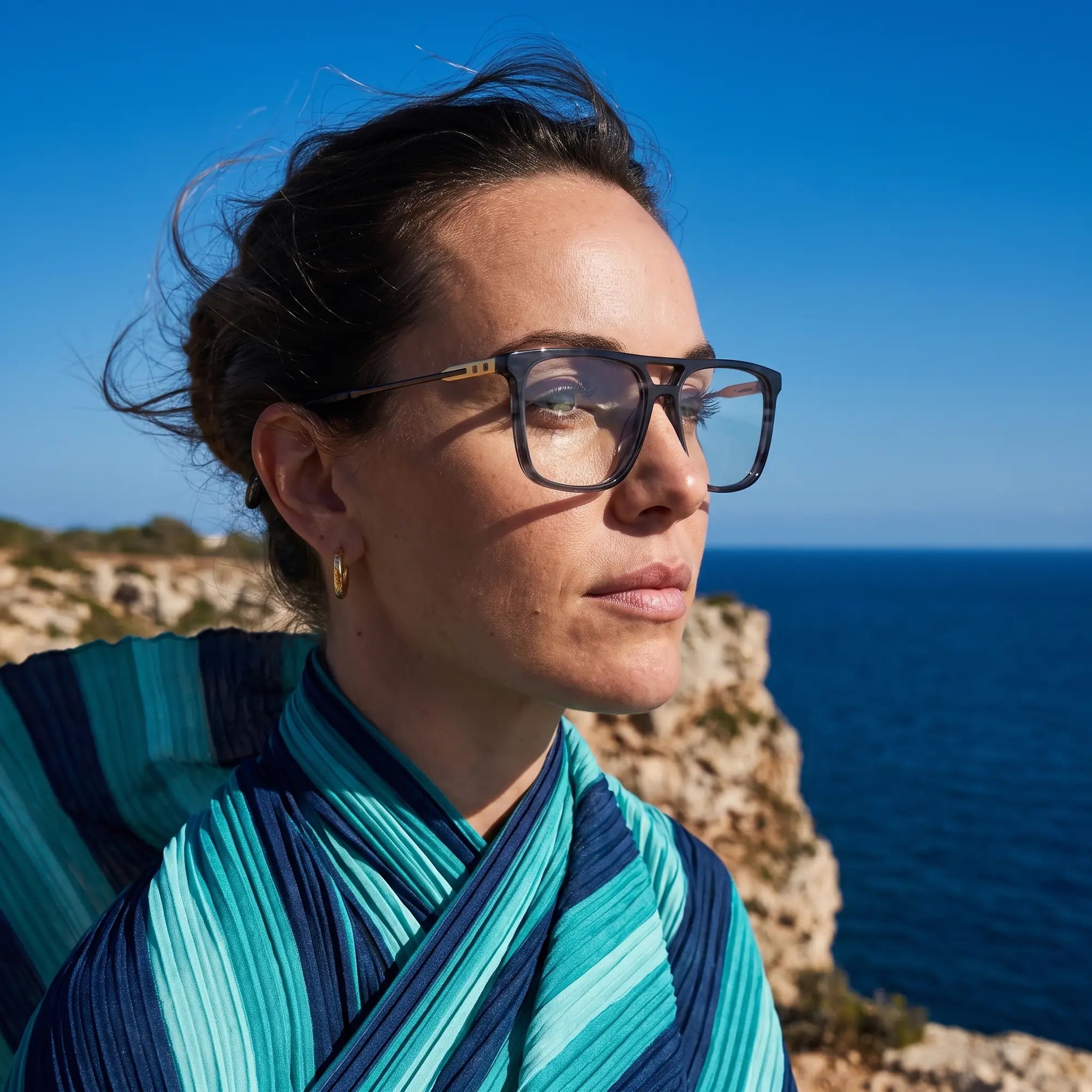 Fiore 10177 eyeglasses in grey, worn by a model – campaign portrait, windswept portrait over the deep blue sea