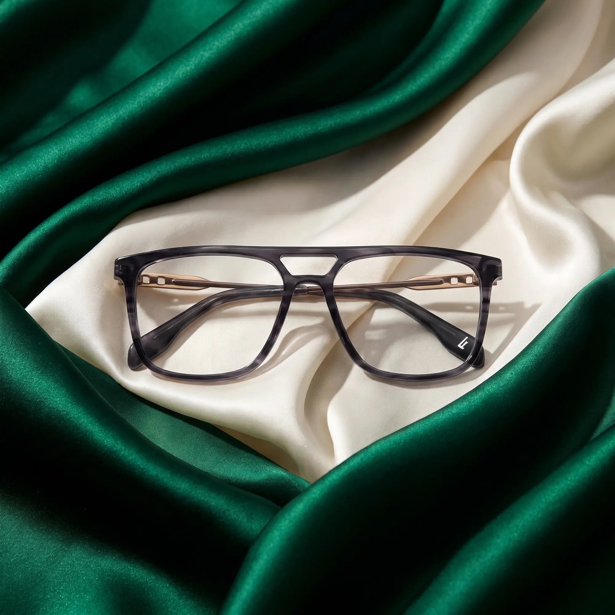 Fiore 10177 eyeglasses in grey – resting on draped emerald and ivory silk