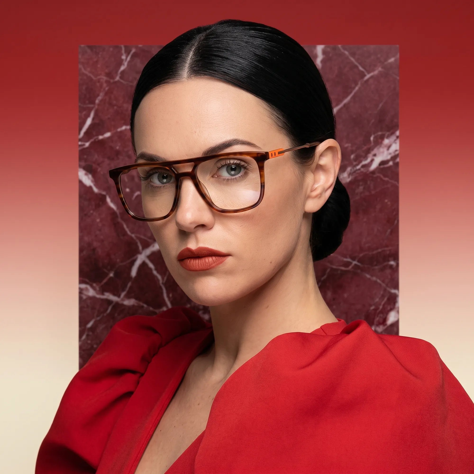 Fiore 10177 eyeglasses in tortoiseshell, worn by a model – campaign portrait, red marble backdrop and draped scarlet dress