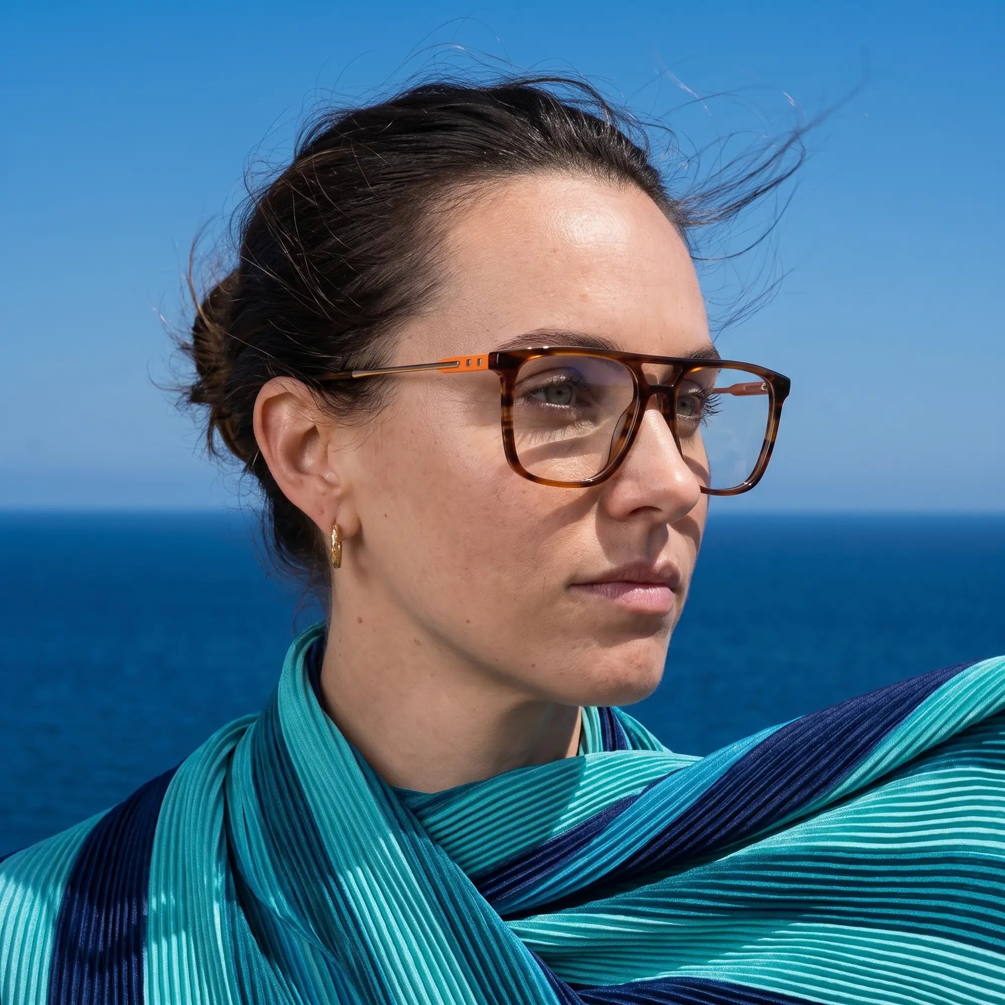 Fiore 10177 eyeglasses in tortoiseshell, worn by a model – campaign portrait, windswept portrait over the deep blue sea