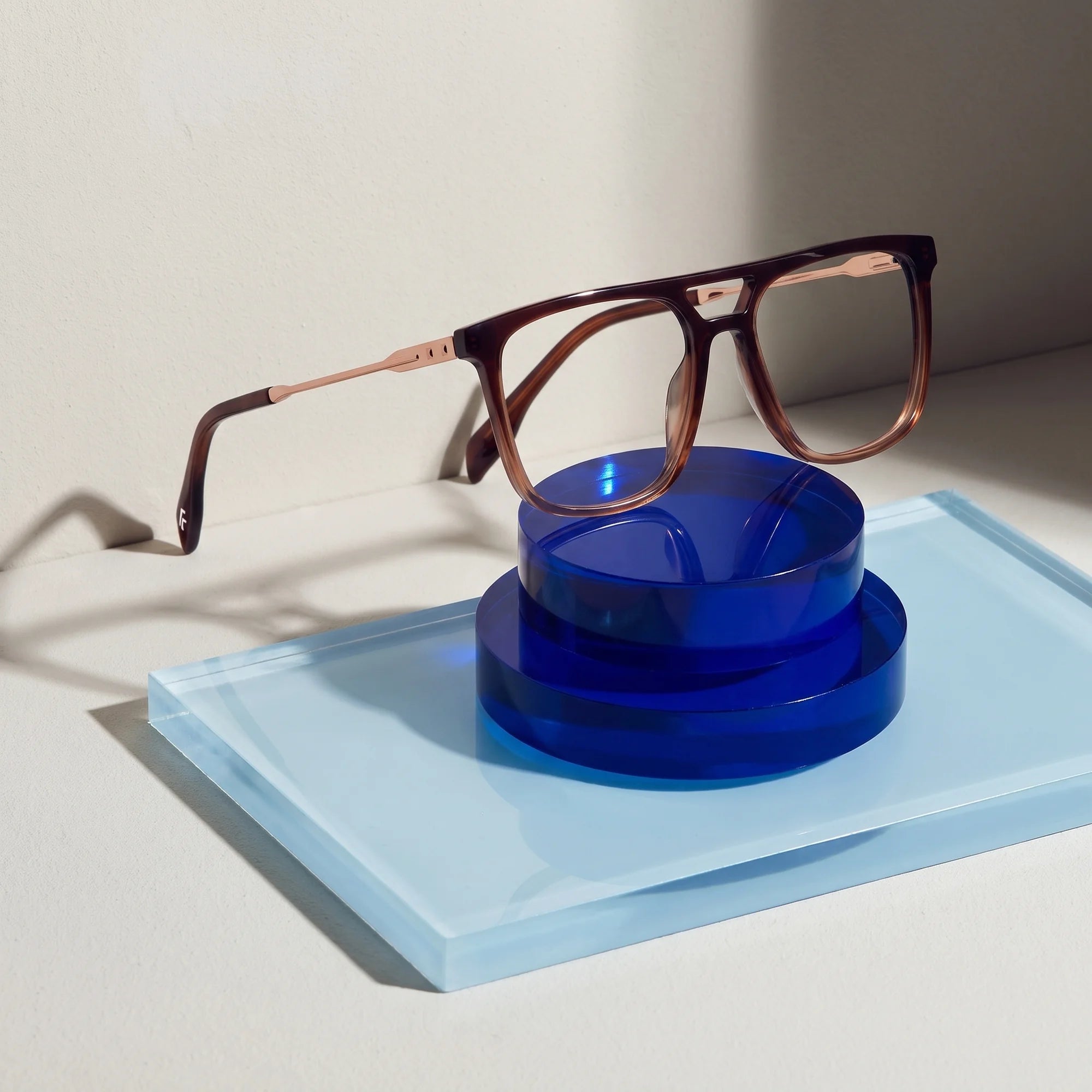 Fiore 10177 eyeglasses in brown – on a cobalt acrylic disc in soft daylight