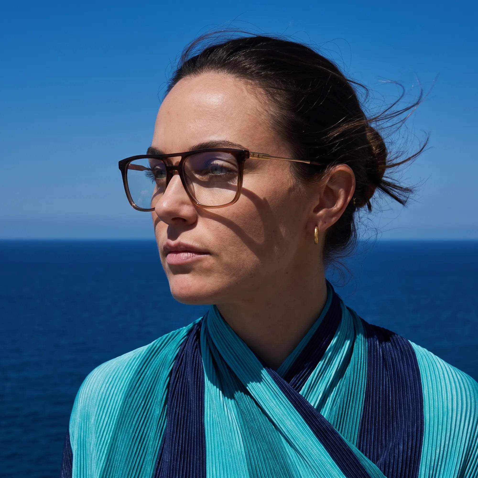 Fiore 10177 eyeglasses in brown, worn by a model – campaign portrait, windswept portrait over the deep blue sea