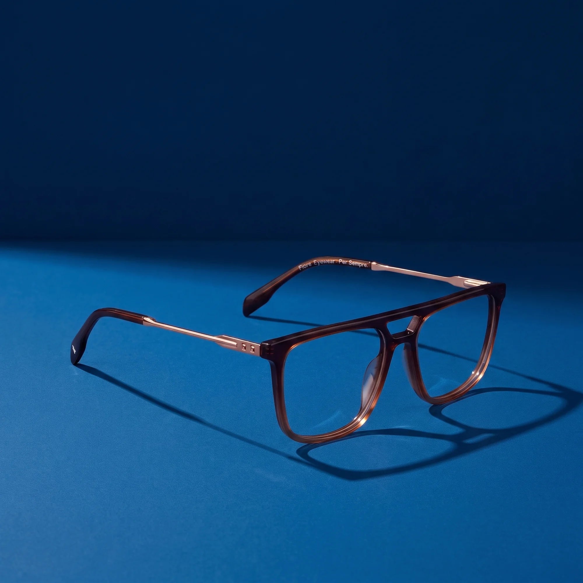 Fiore 10177 eyeglasses in brown – hero still life against a deep midnight blue backdrop
