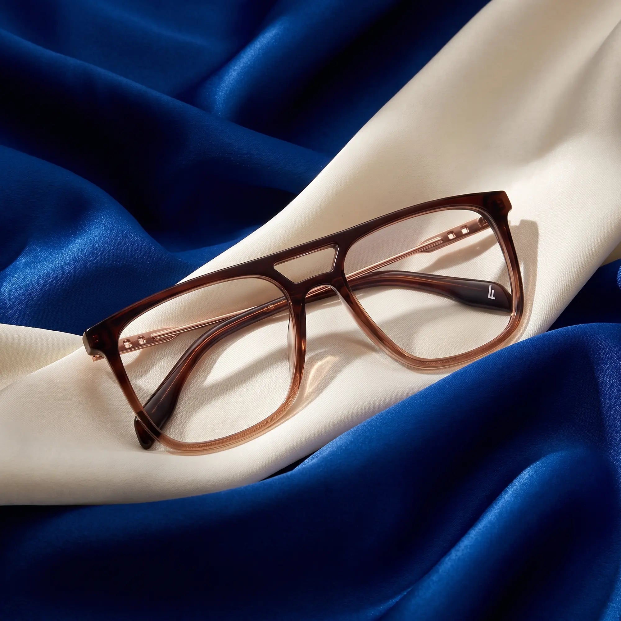 Fiore 10177 eyeglasses in brown – resting on draped cobalt and ivory silk