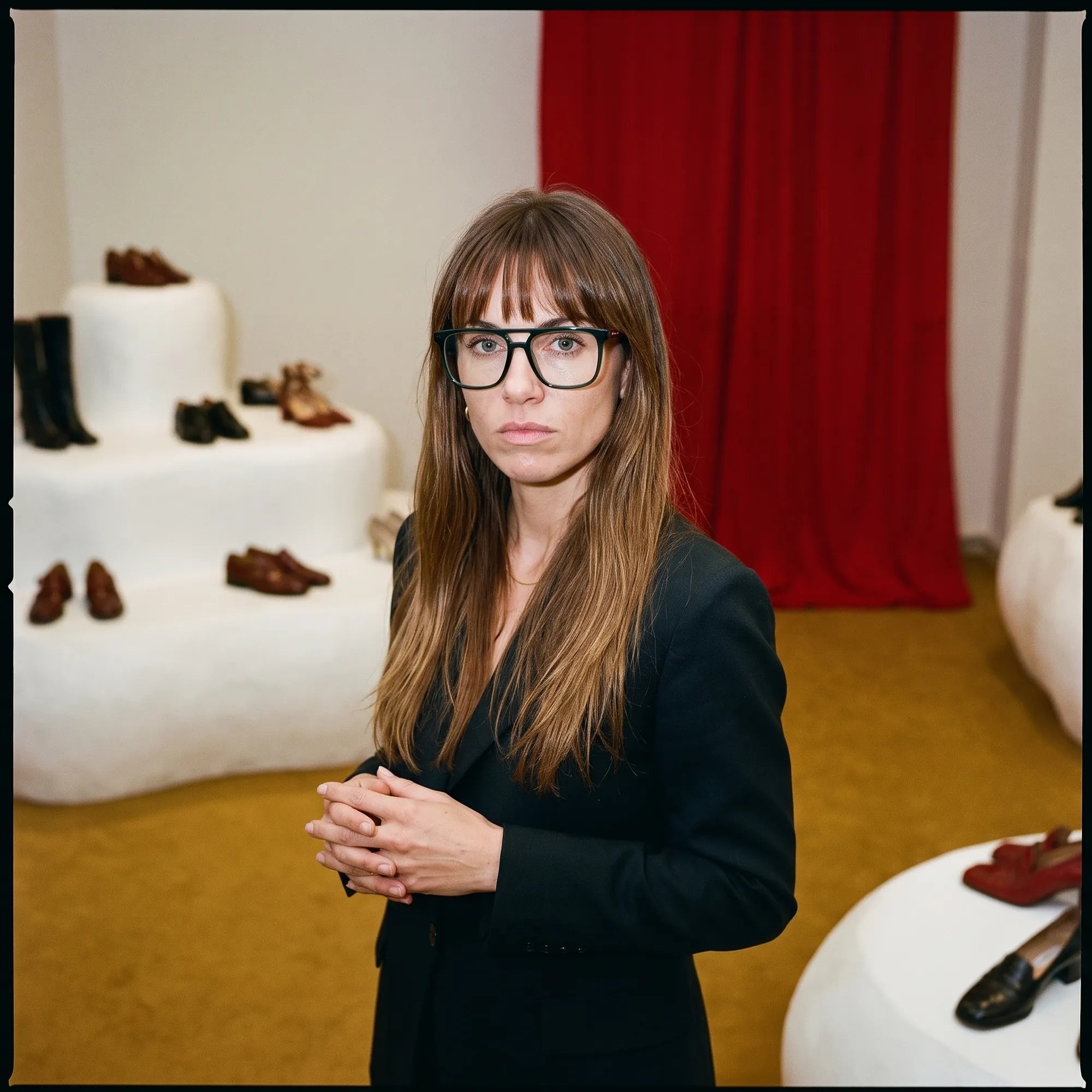 Fiore 10177 eyeglasses in green, worn by a model – campaign portrait, gallery scene with red curtain and plinths